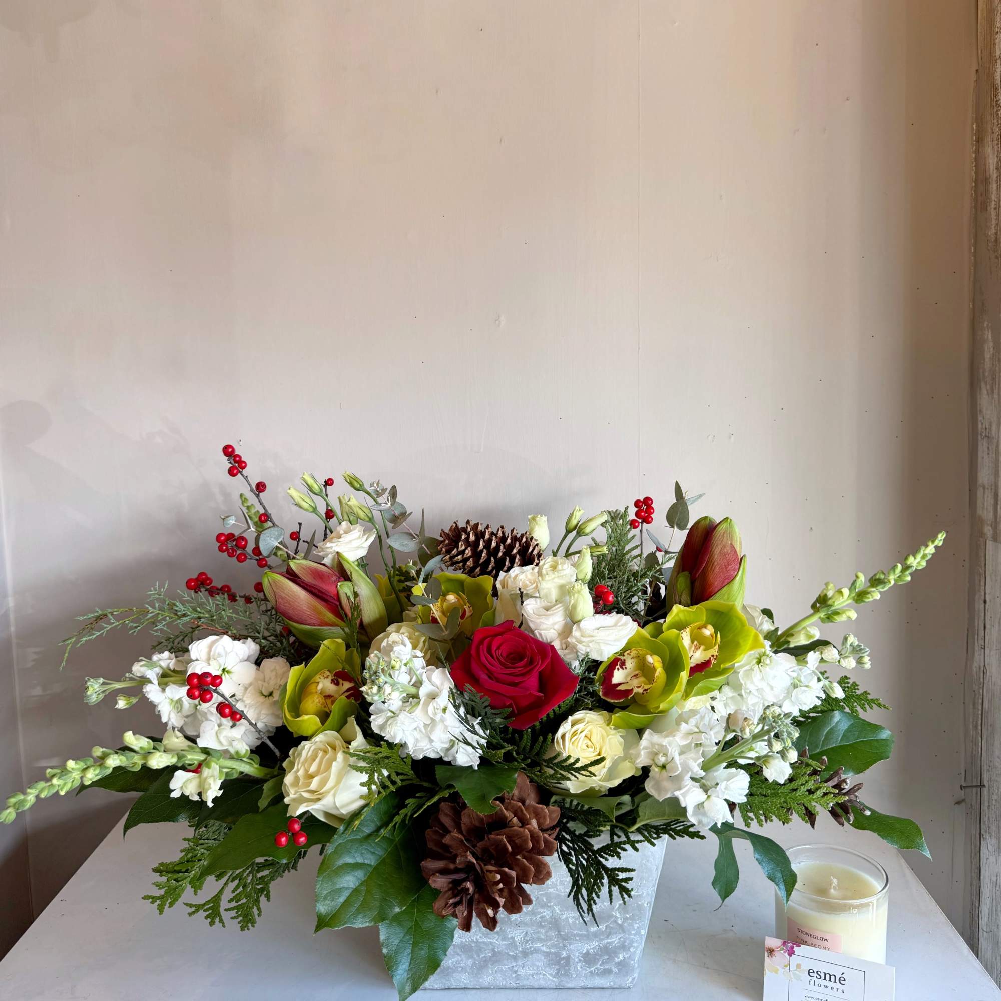 A low and long, premium centerpiece featuring Amaryllis, Cymbidium orchids, roses, lisianthus