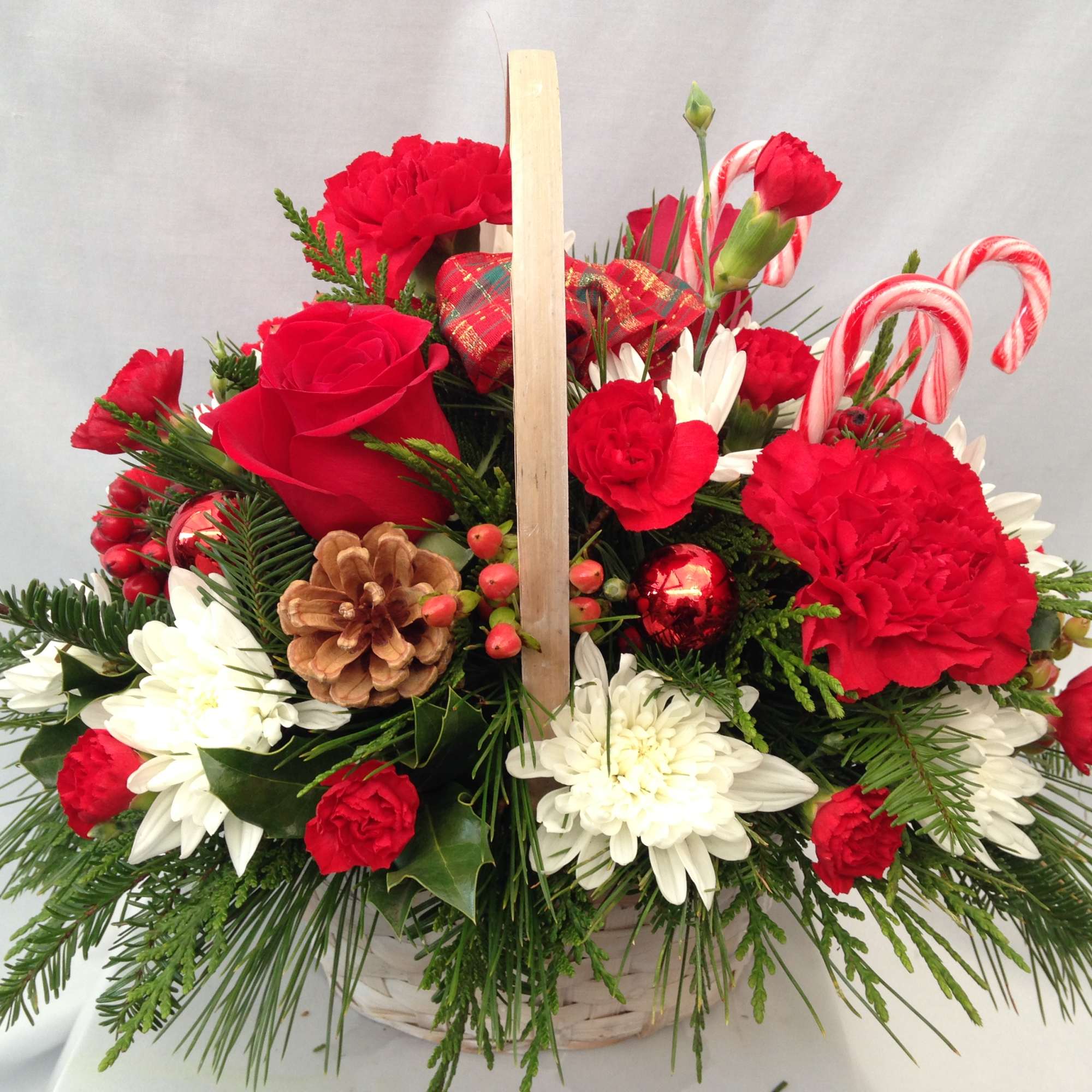 Delight someone with this wicker basket filled with holiday evergreens, long lasting