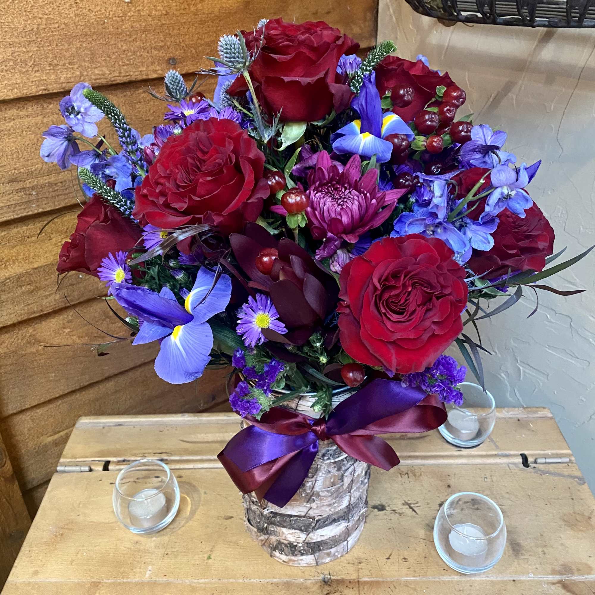 Bouquet filled with roses and specialty burgundy and purple flowers