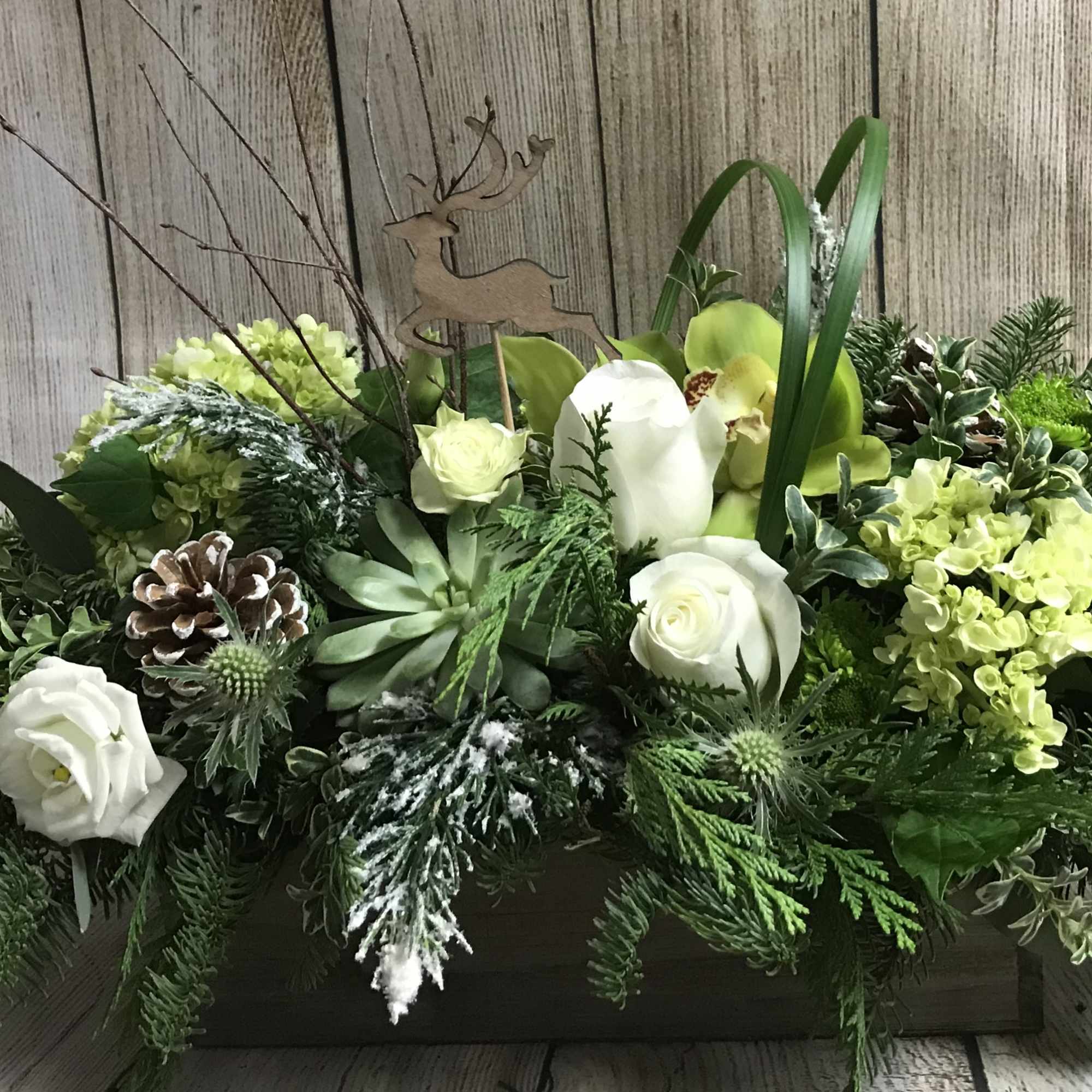 A winter mix of assorted foliage, natural palette of roses, orchids, lisianthus
