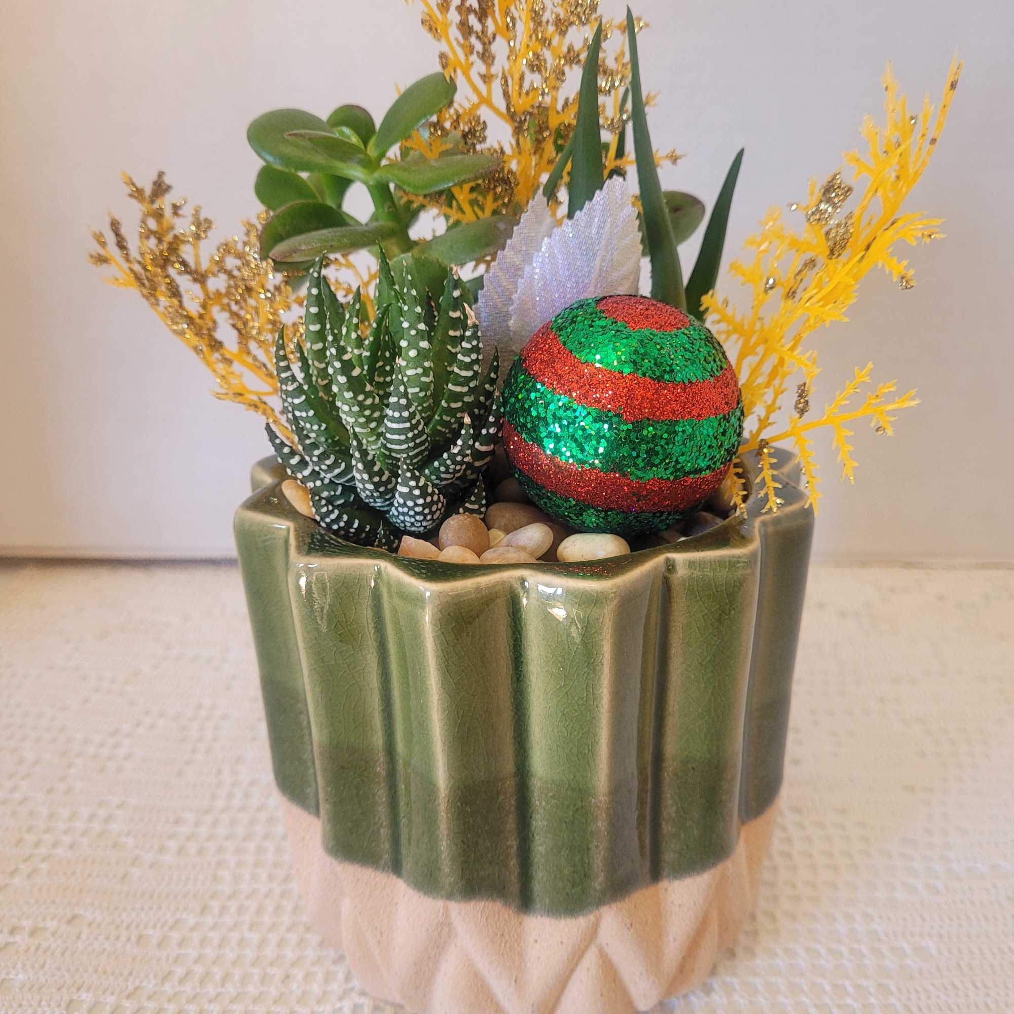 A lovely green ceramic planted with succulents and decked out with seasonal