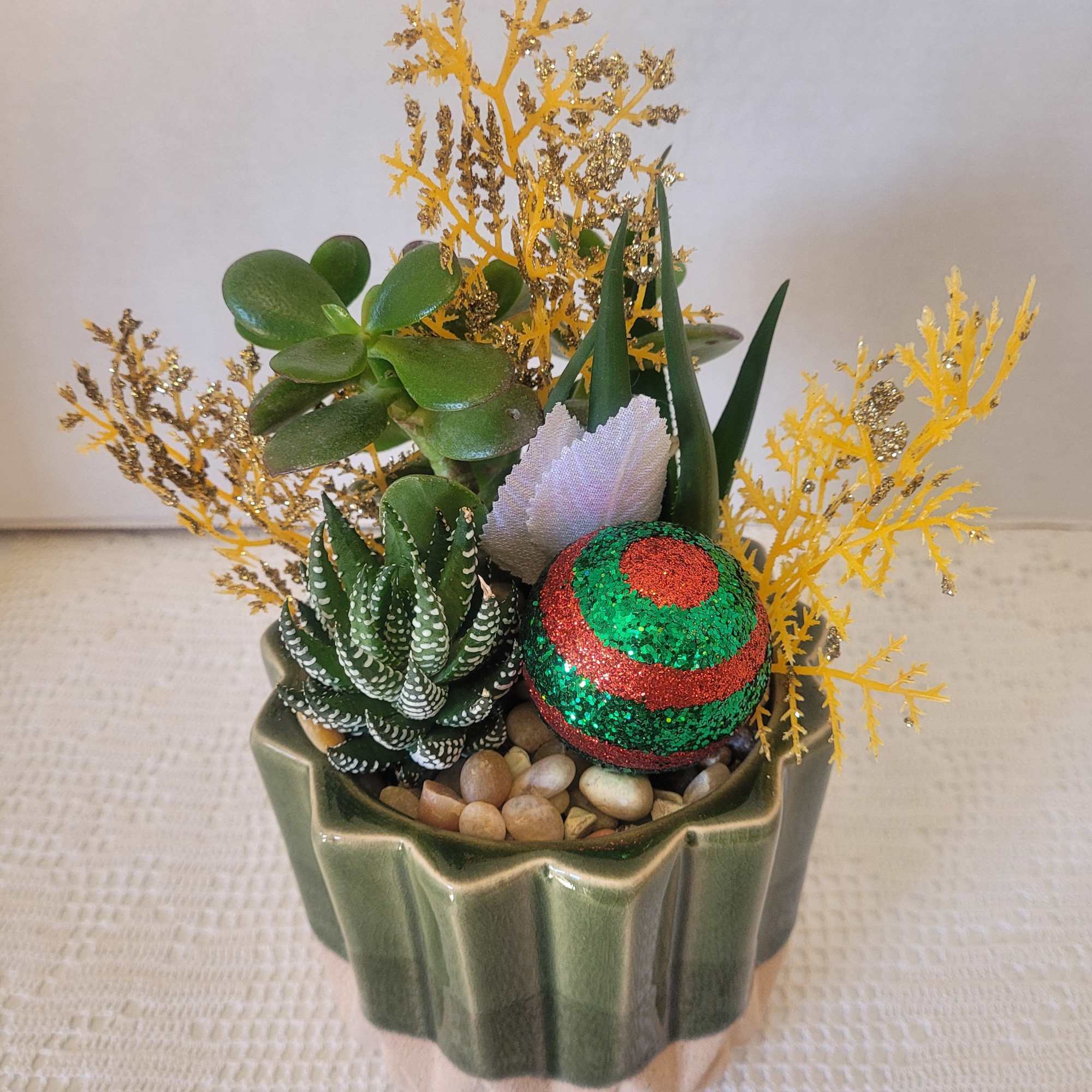 A lovely green ceramic planted with succulents and decked out with seasonal