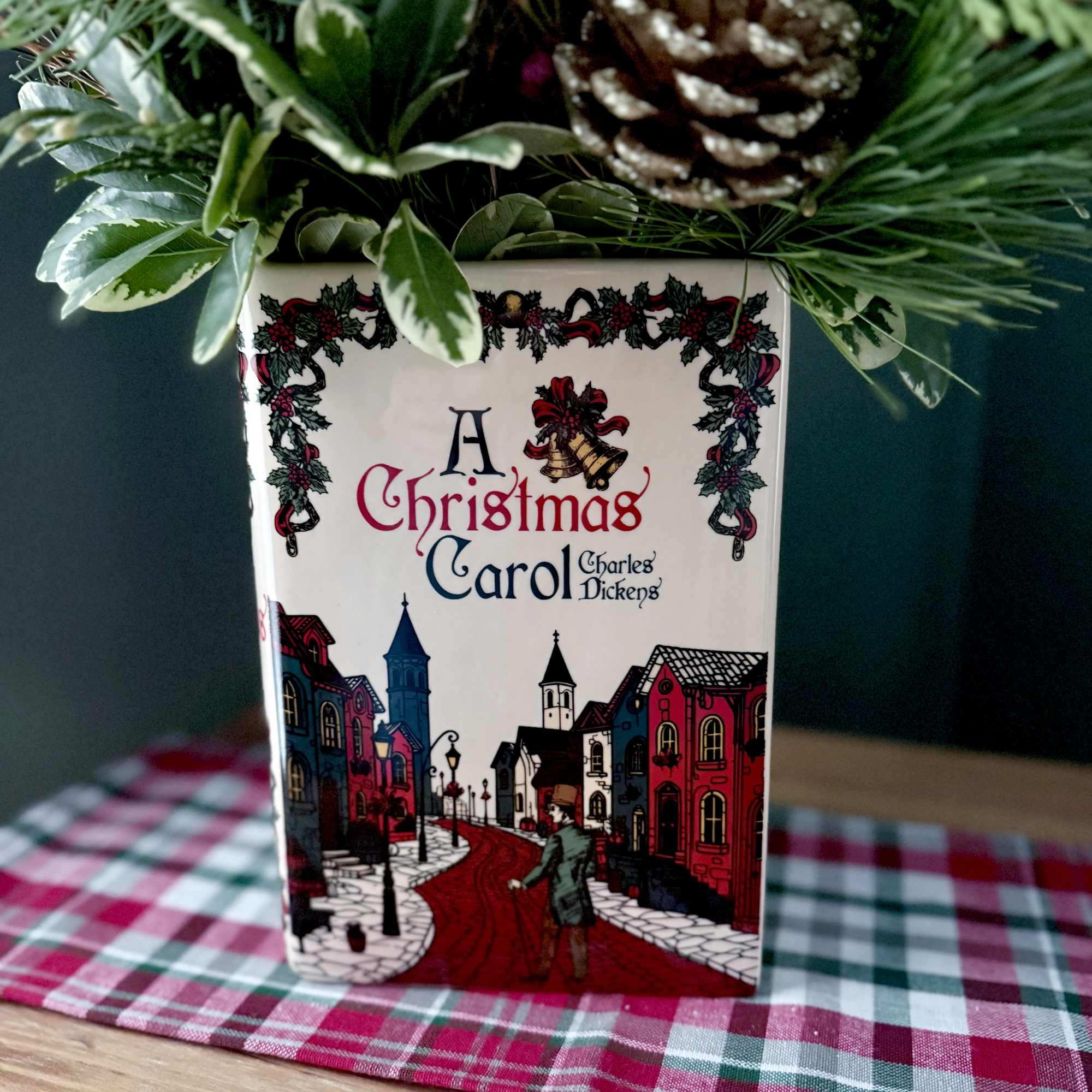 A ceramic vase in the shape of a book featuring a Christmas
