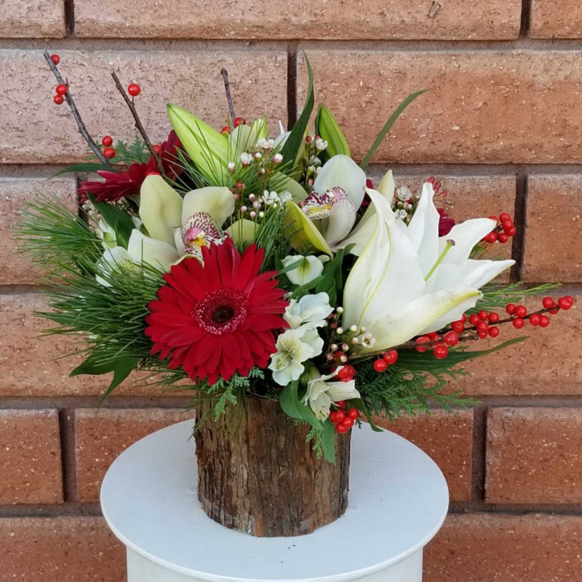 A festive and delightful arrangement of crystal blanca lilies, cymbidium orchids, red