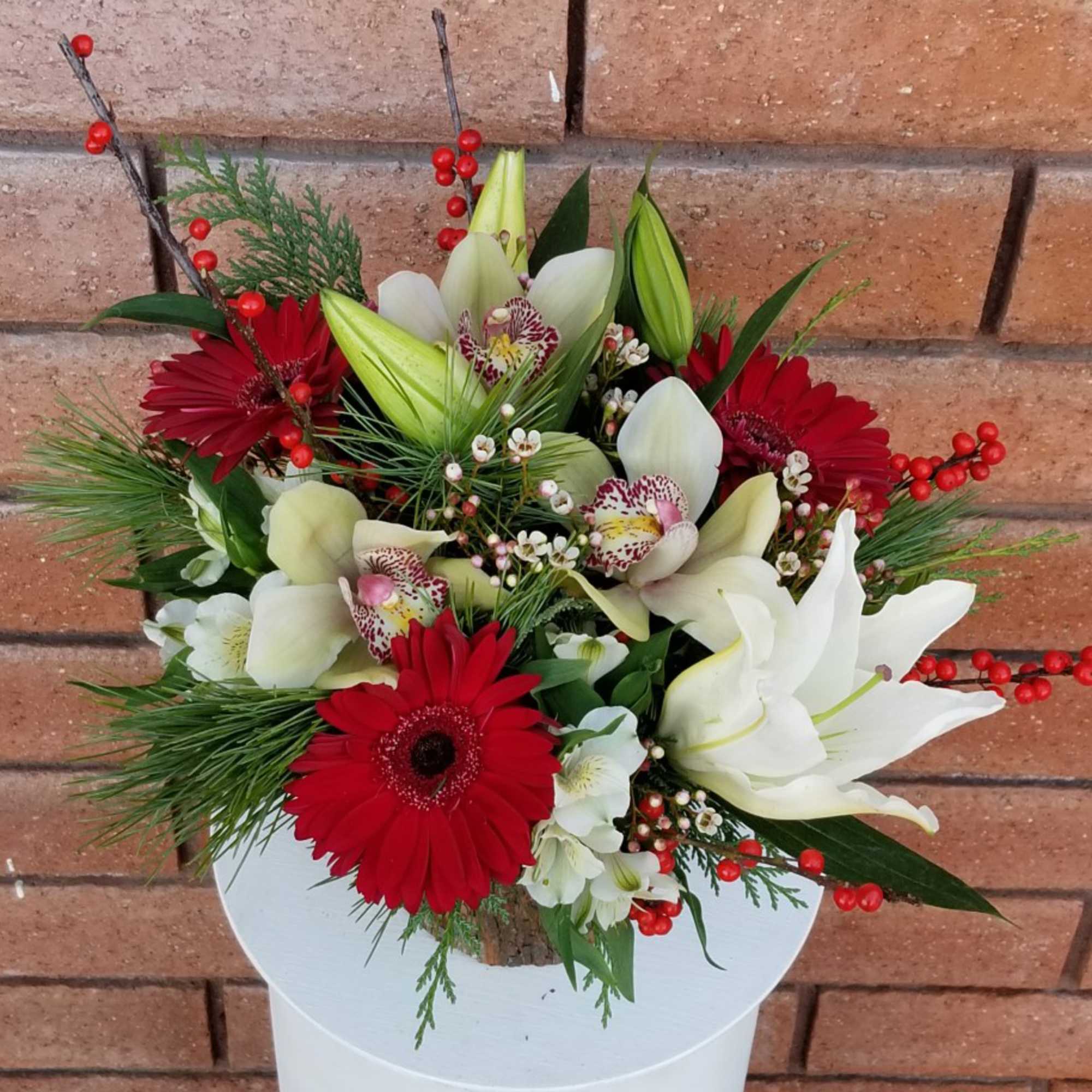 A festive and delightful arrangement of crystal blanca lilies, cymbidium orchids, red