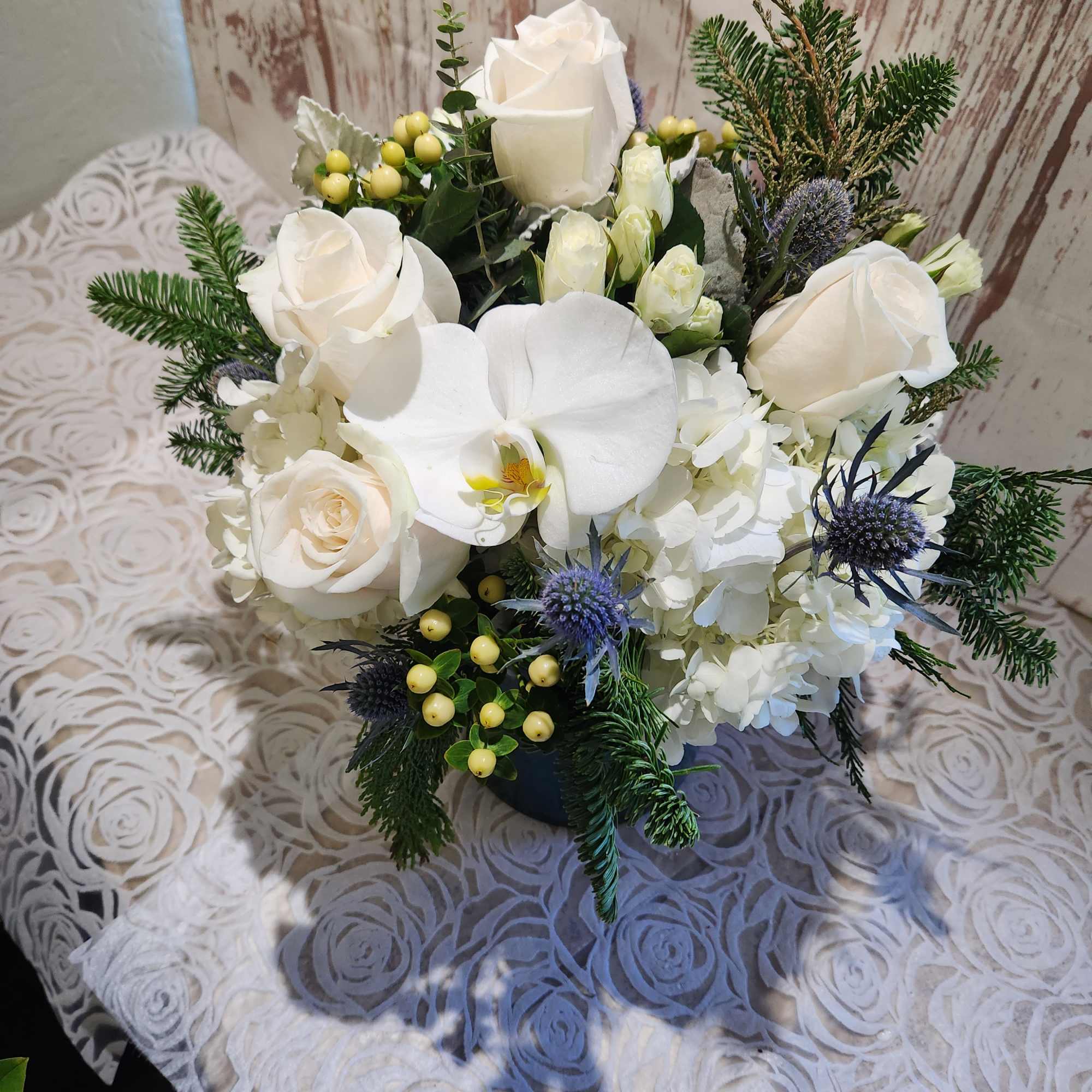 Our blue and white arrangement of fresh blue thistle, white roses, 