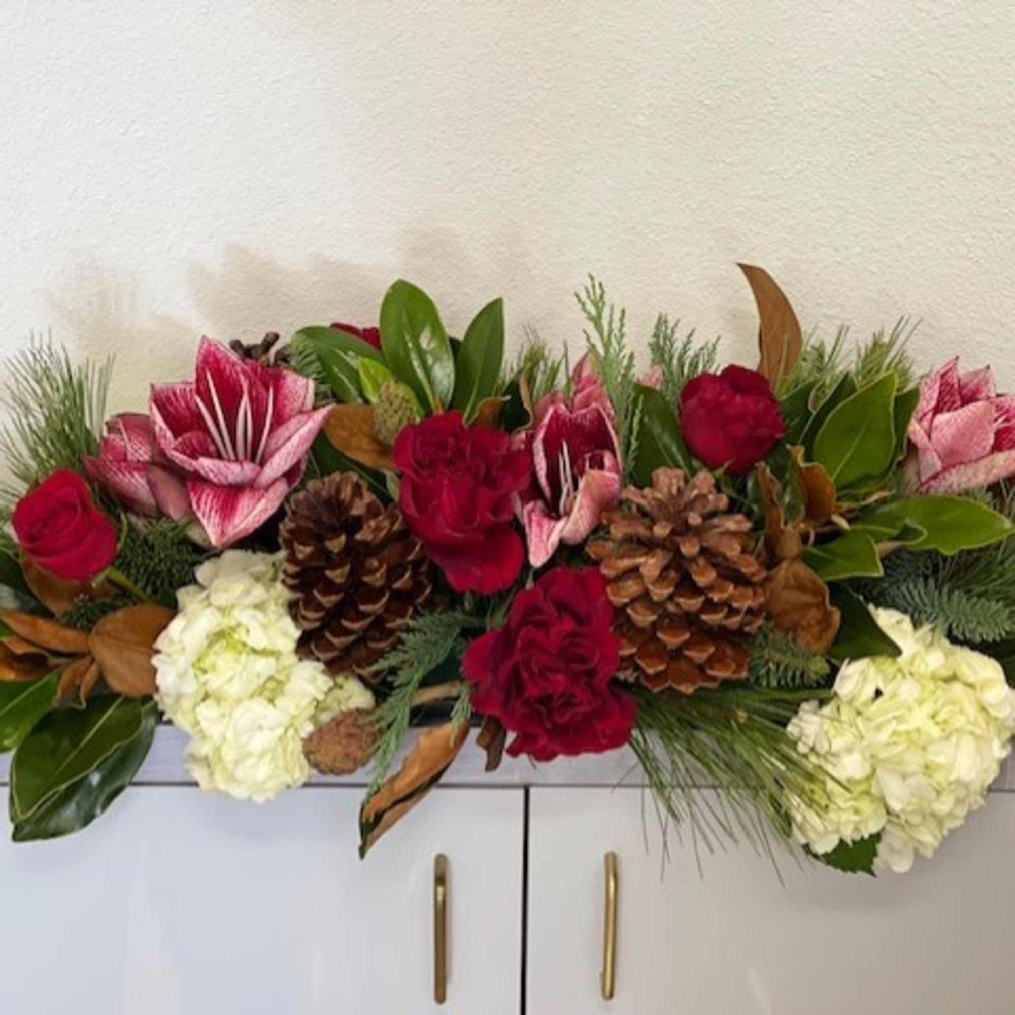 A gorgeous centerpiece with Amaryllis, Roses, Hydrangea and seasonal adornments.