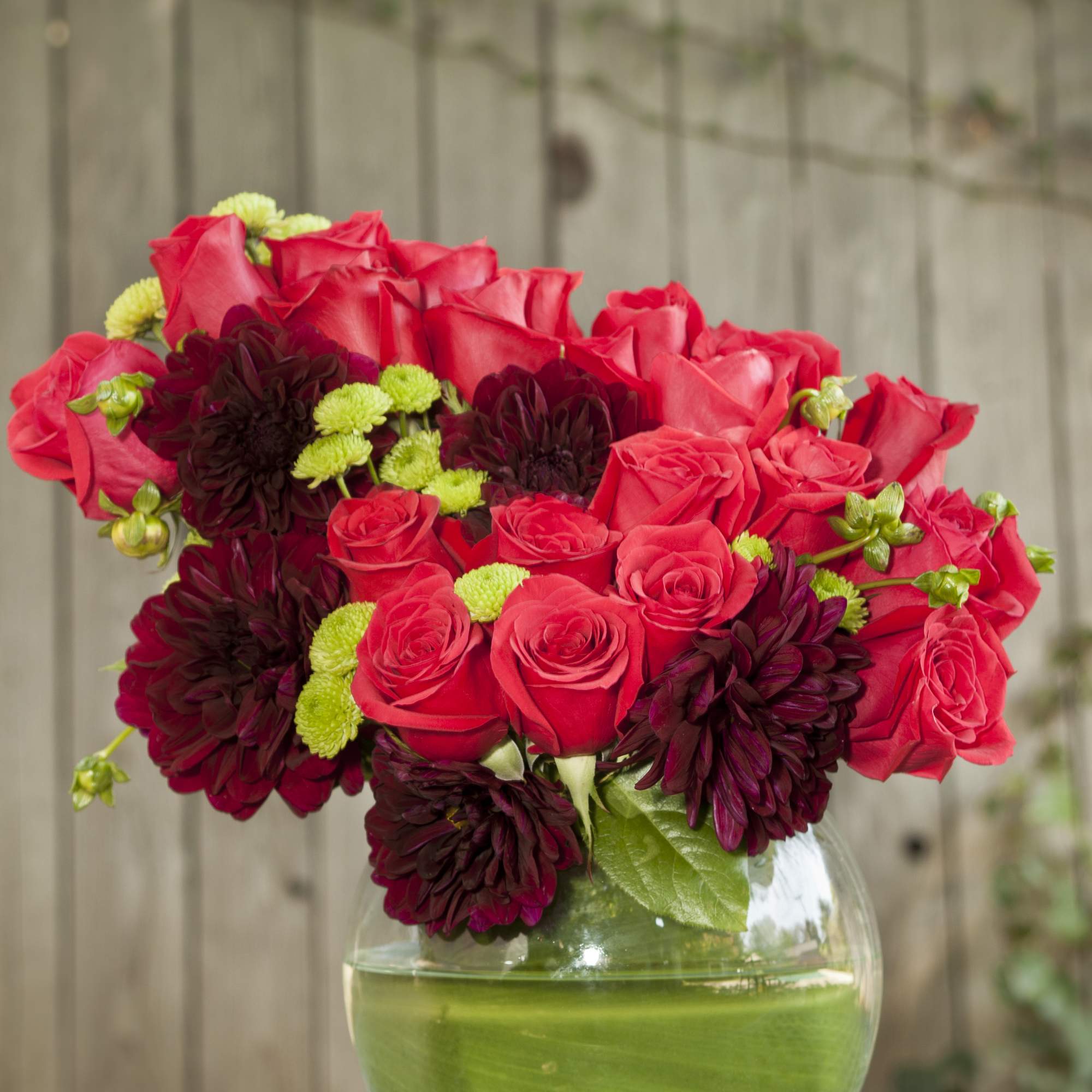 Gorgeous red roses, vibrant burgundy dahlias, and more beautifully crafted in a