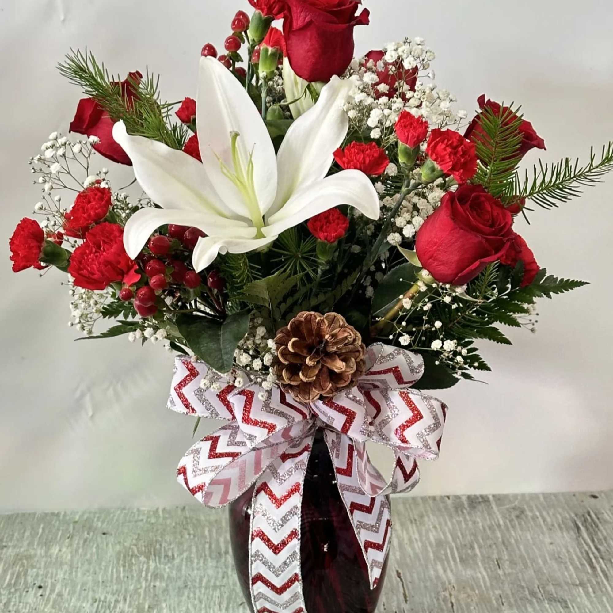 This stunning arrangement includes vibrant red roses, elegant white lilies, charming red