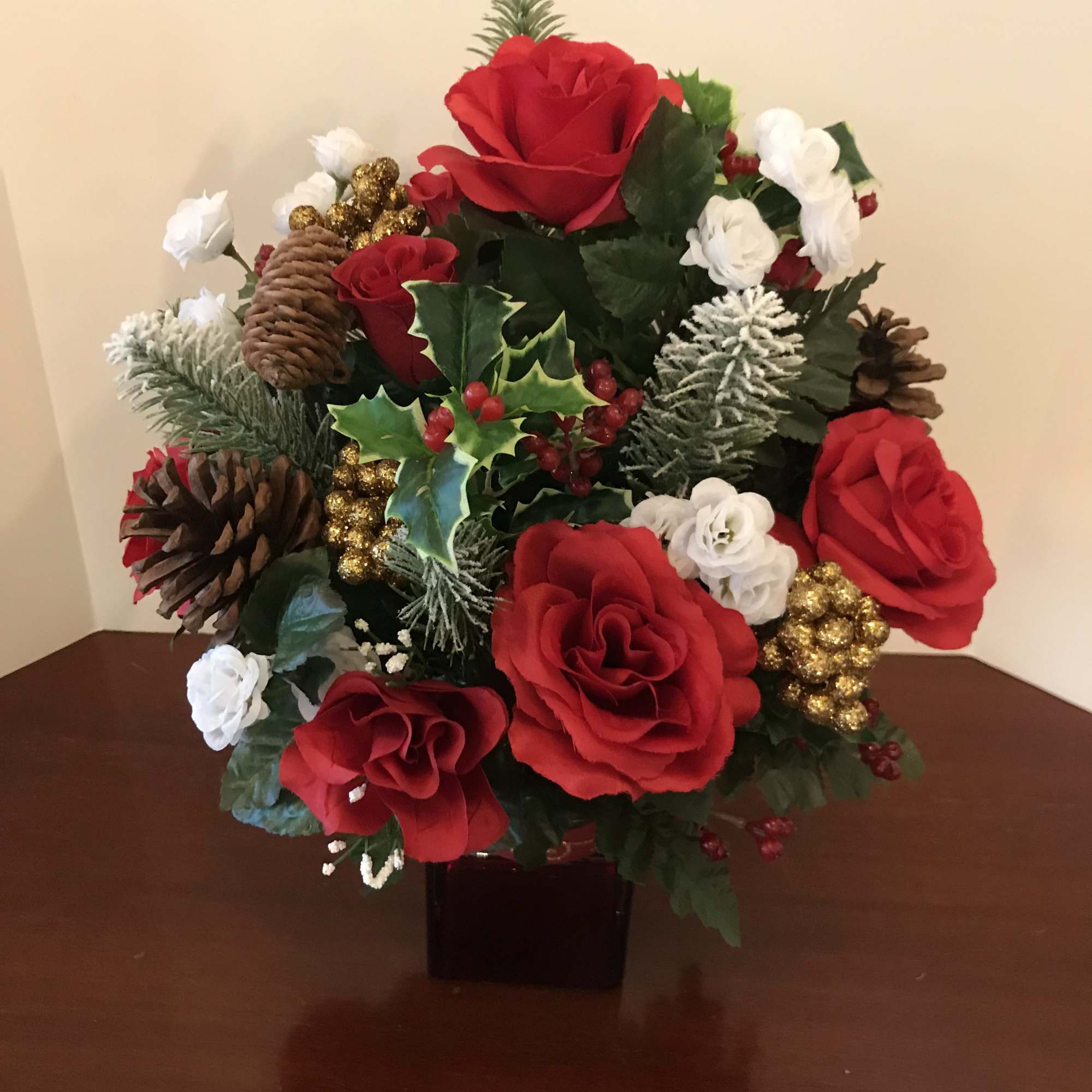 A beautiful arrangement of red roses and assorted holiday greens nestled with