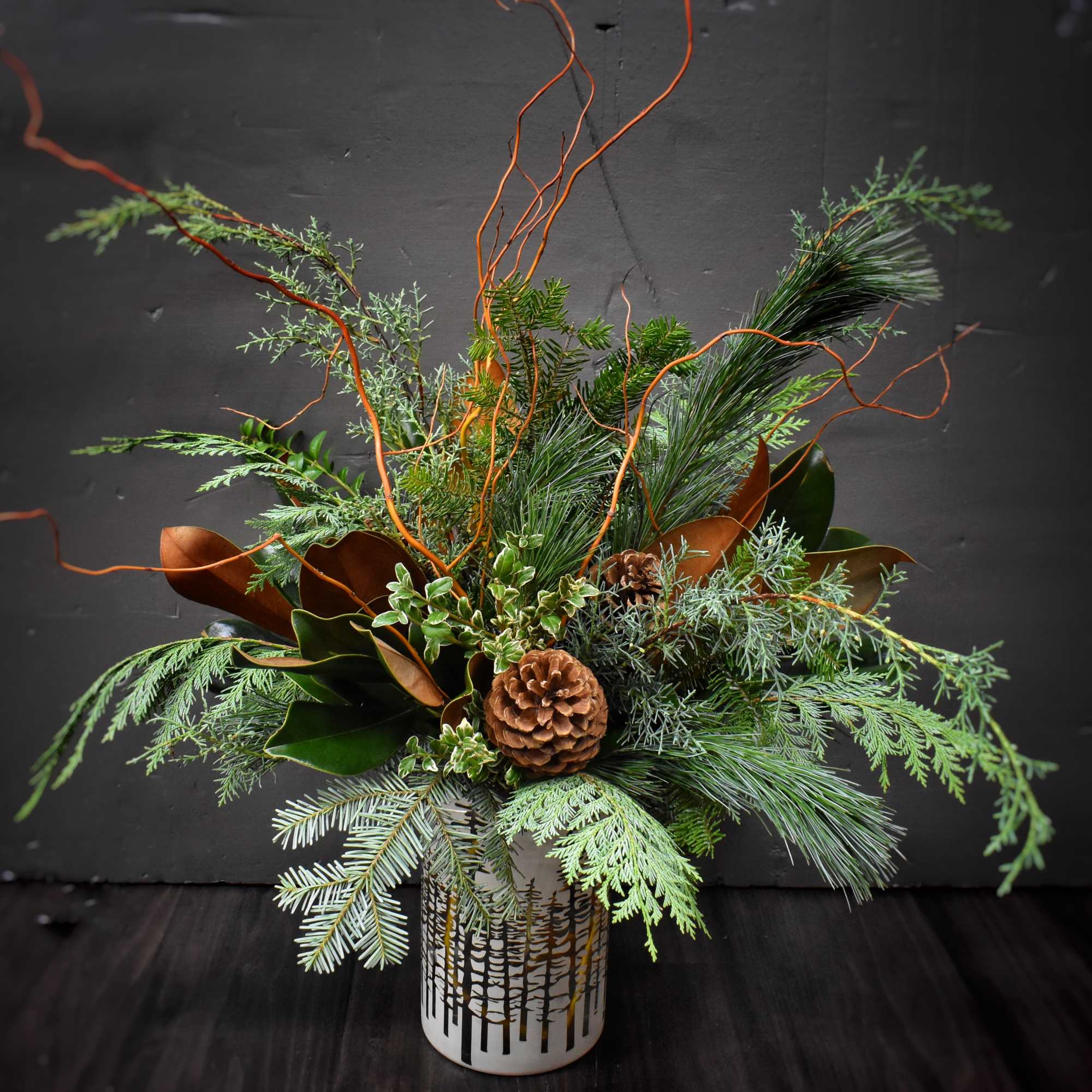 A large arrangement of seasonal greens and evergreens, branches, and pinecones in