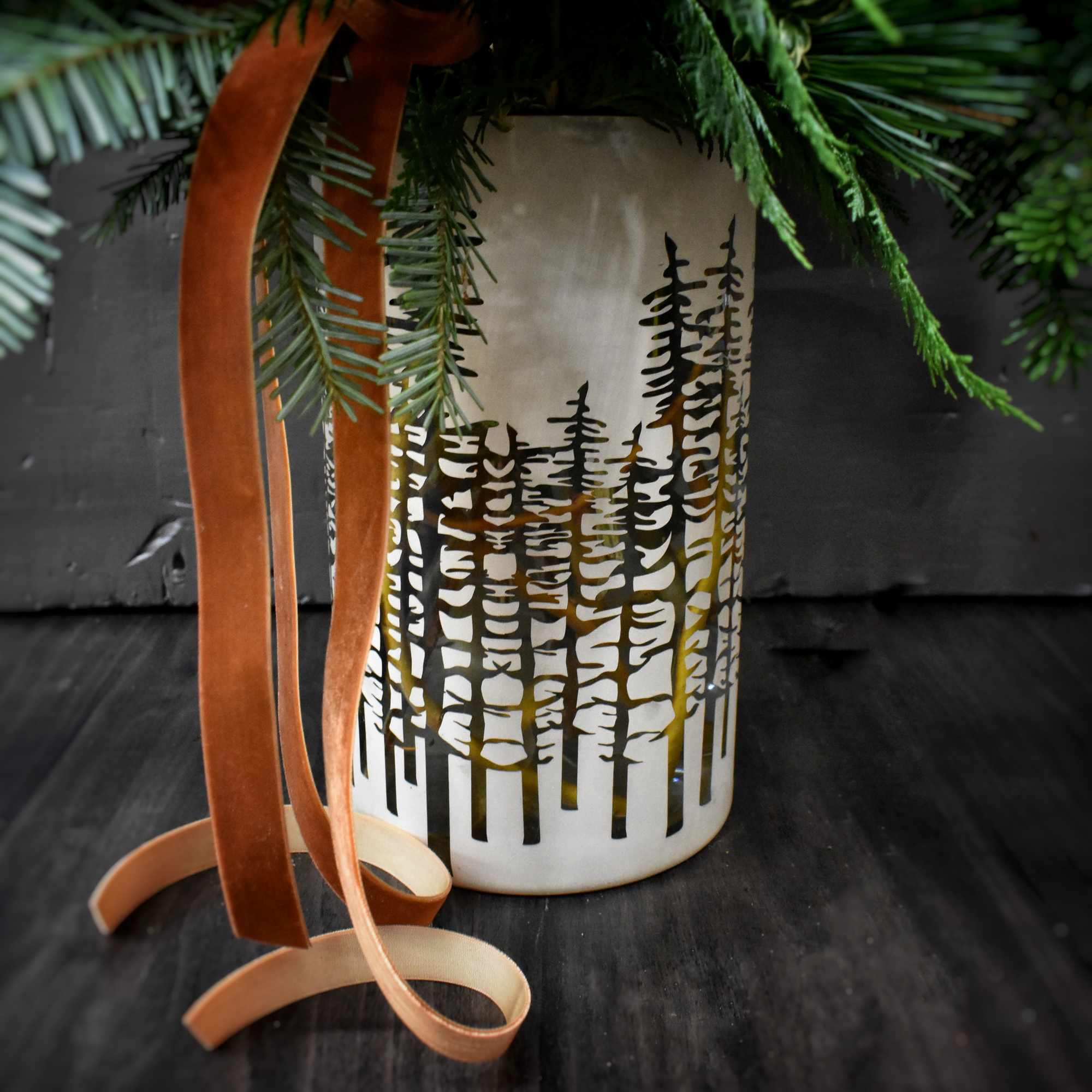 A large arrangement of seasonal greens and evergreens, branches, and pinecones in