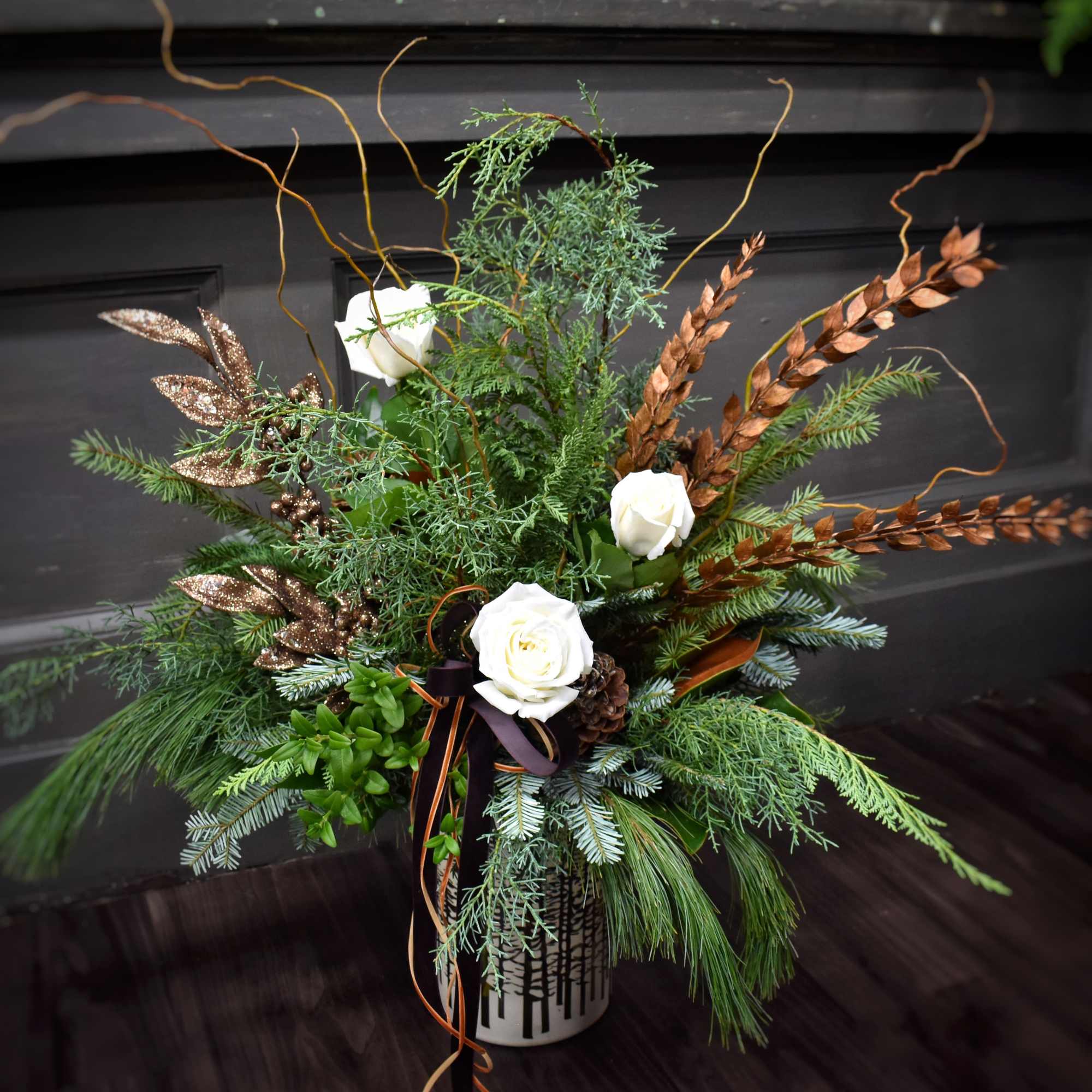 A large arrangement of seasonal greens and evergreens, branches, and pinecones in