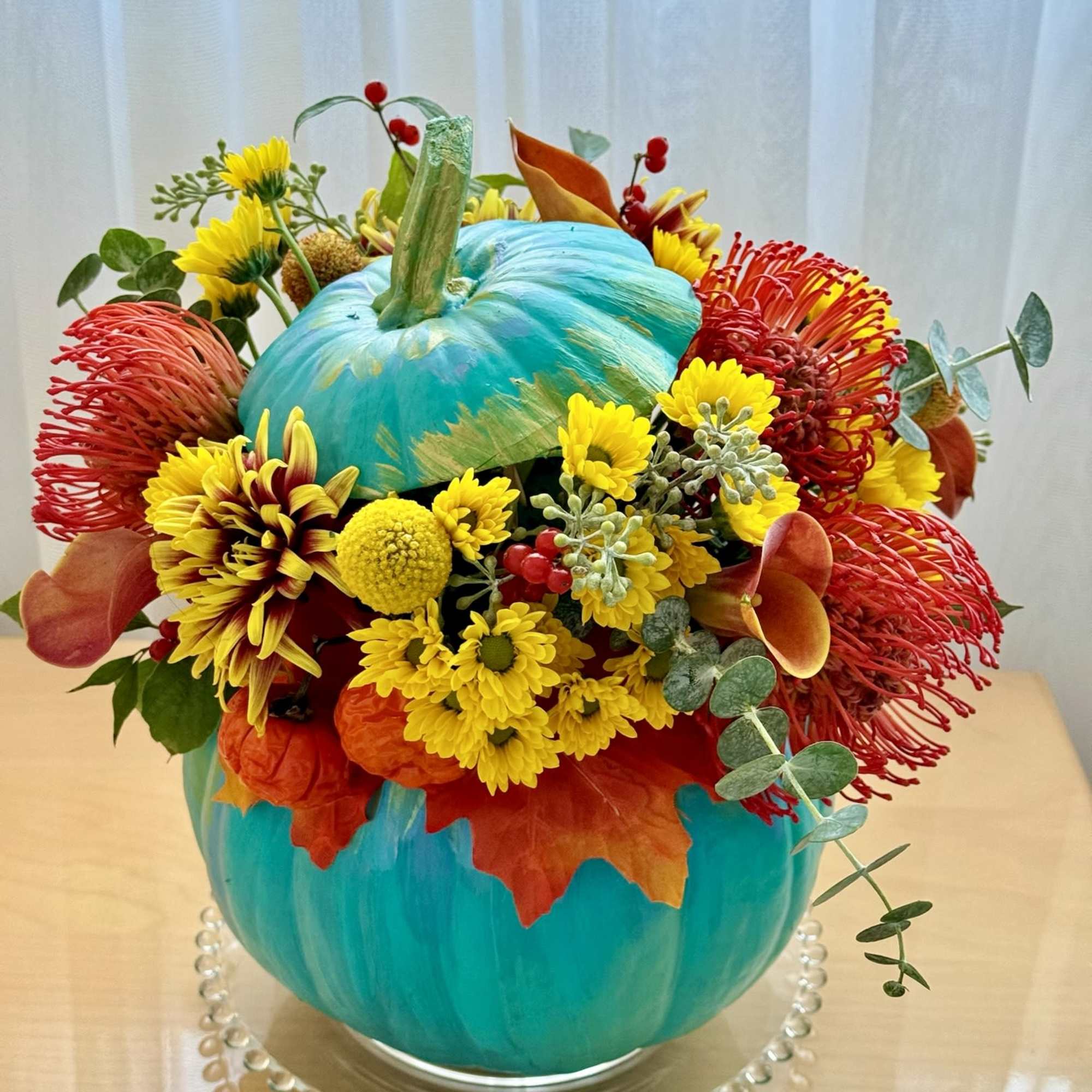This vibrant and playful fall arrangement is designed in a stunning turquoise