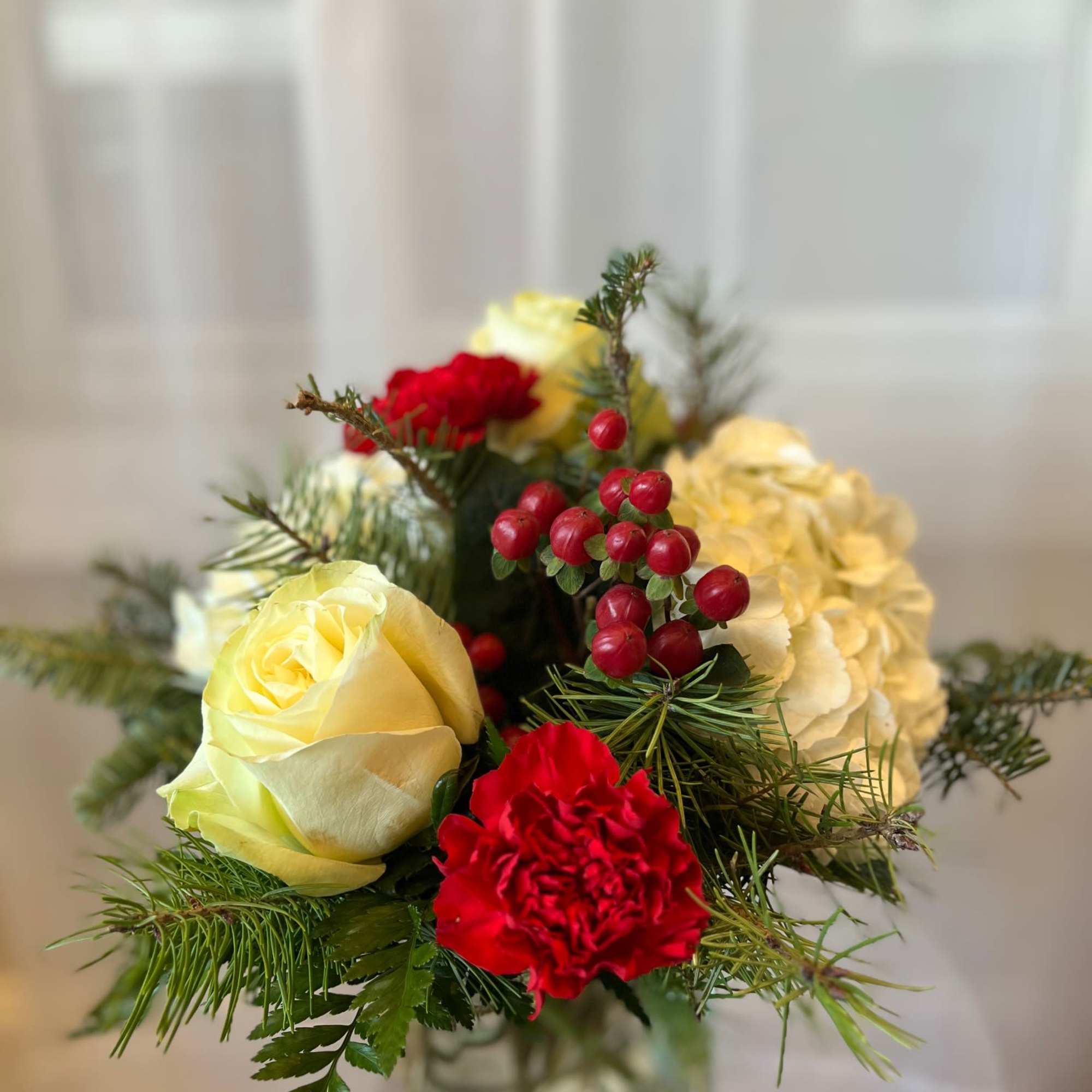 Classic and cozy, this seasonal arrangement blends creamy white blooms with cheerful