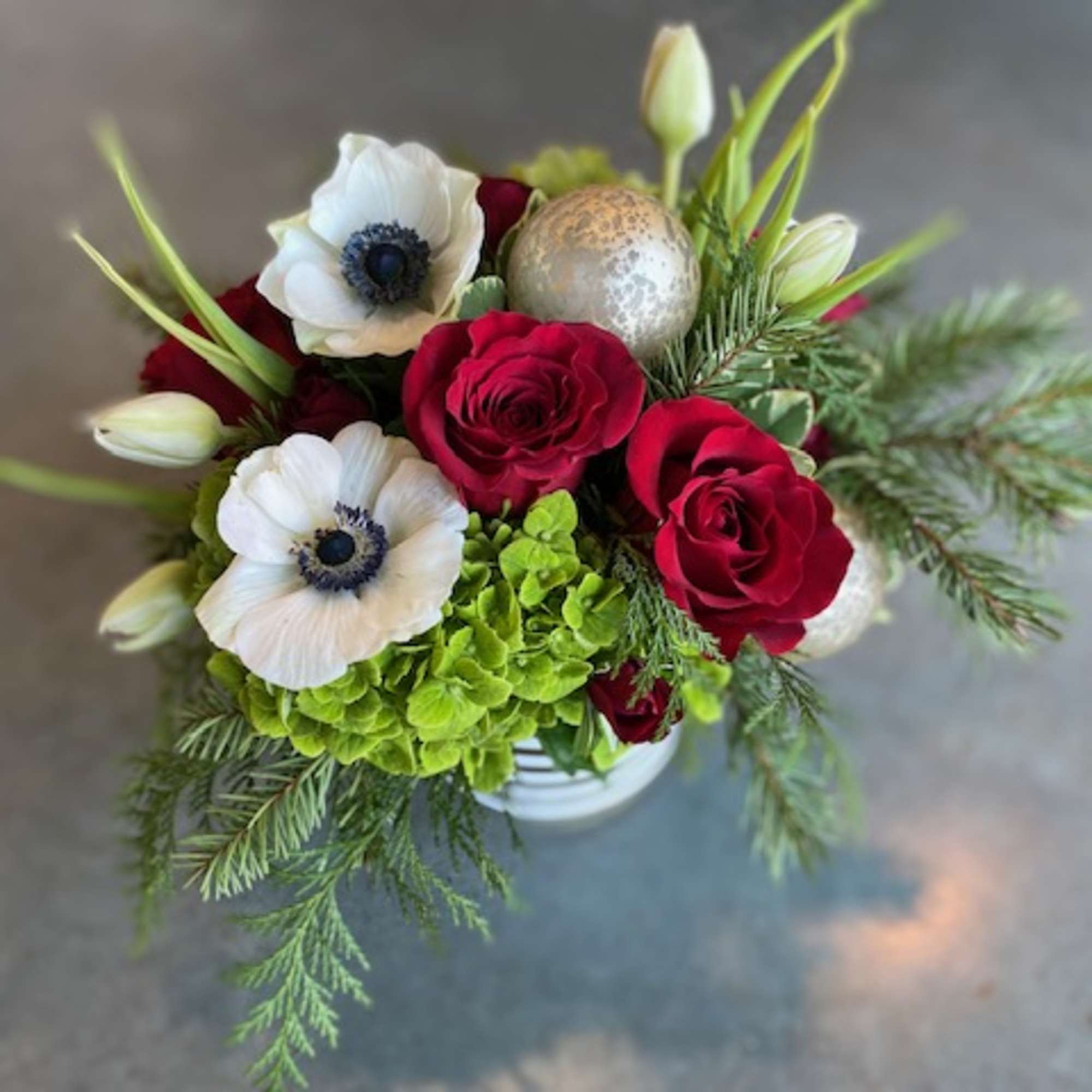 Christmas colors with seasonal flowers, evergreens and holiday accents.