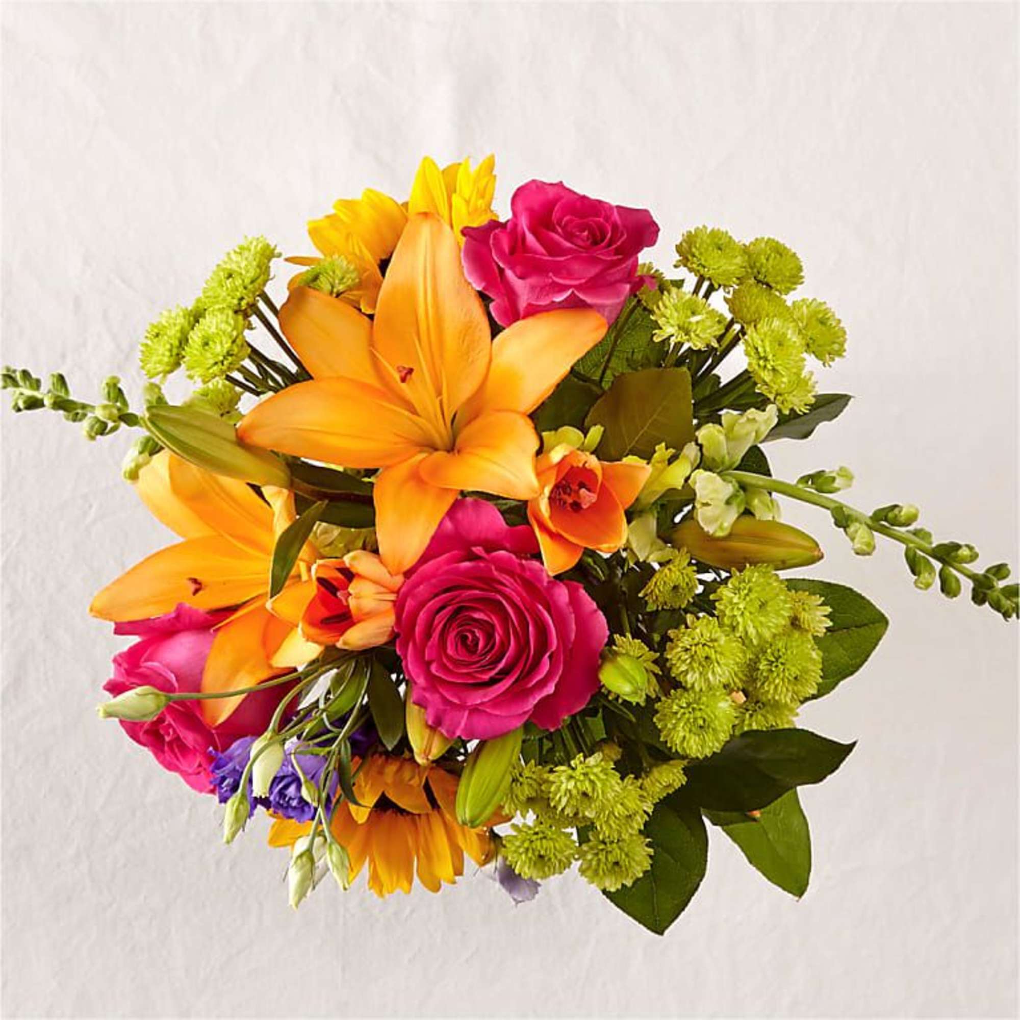 This arrangement features a colorful array of flowers in a clear glass