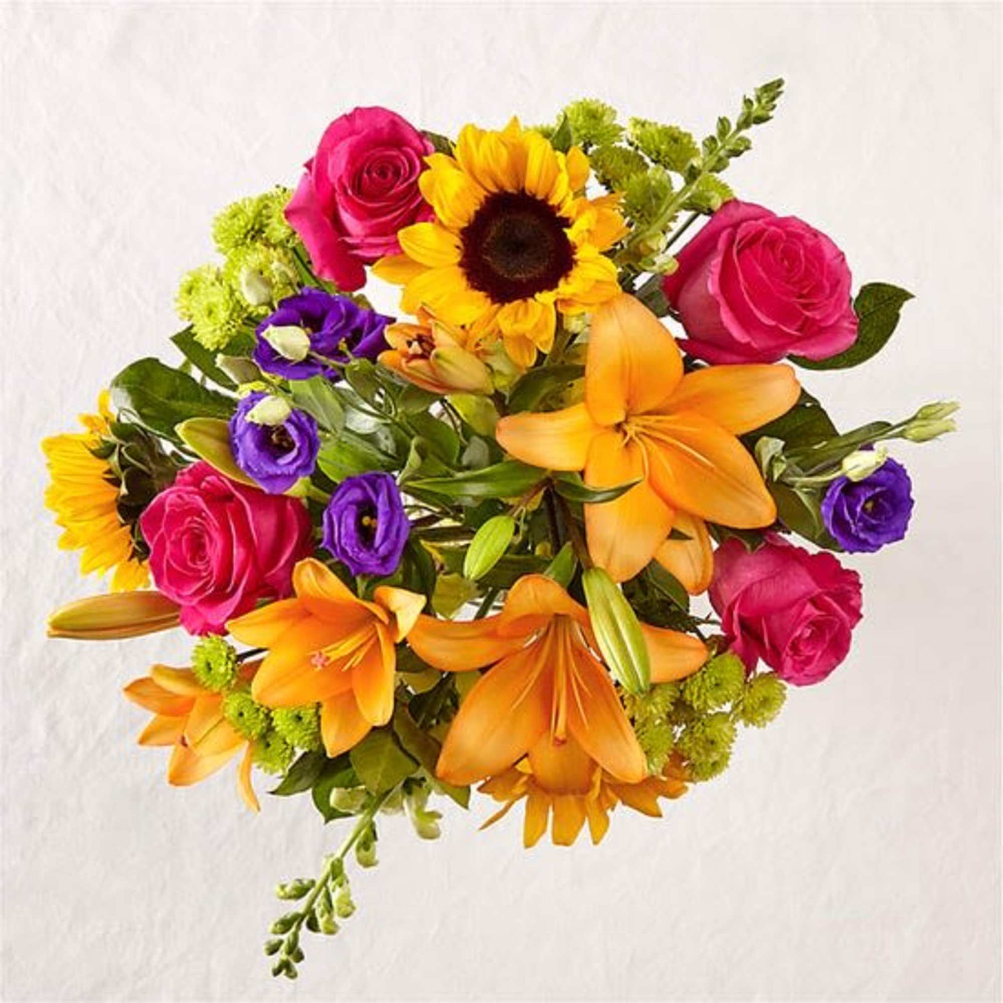This arrangement features a colorful array of flowers in a clear glass