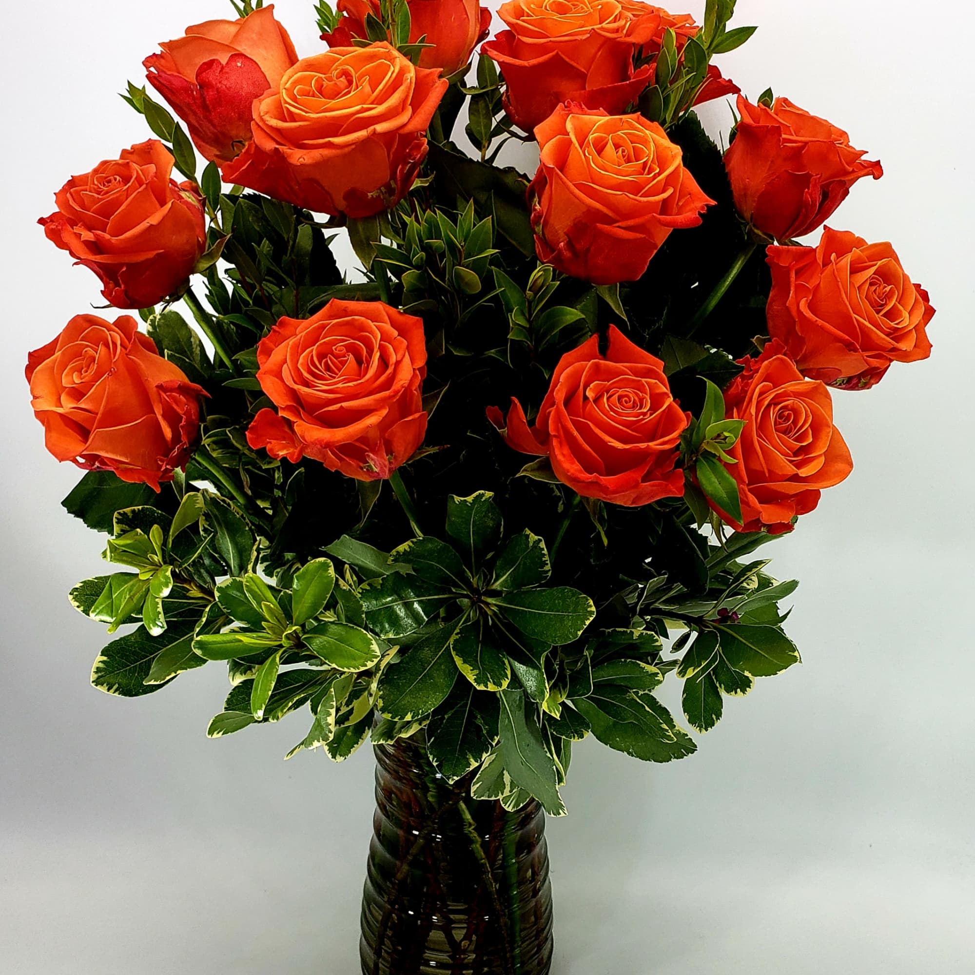 Orange Roses arranged in a clear glass vase.