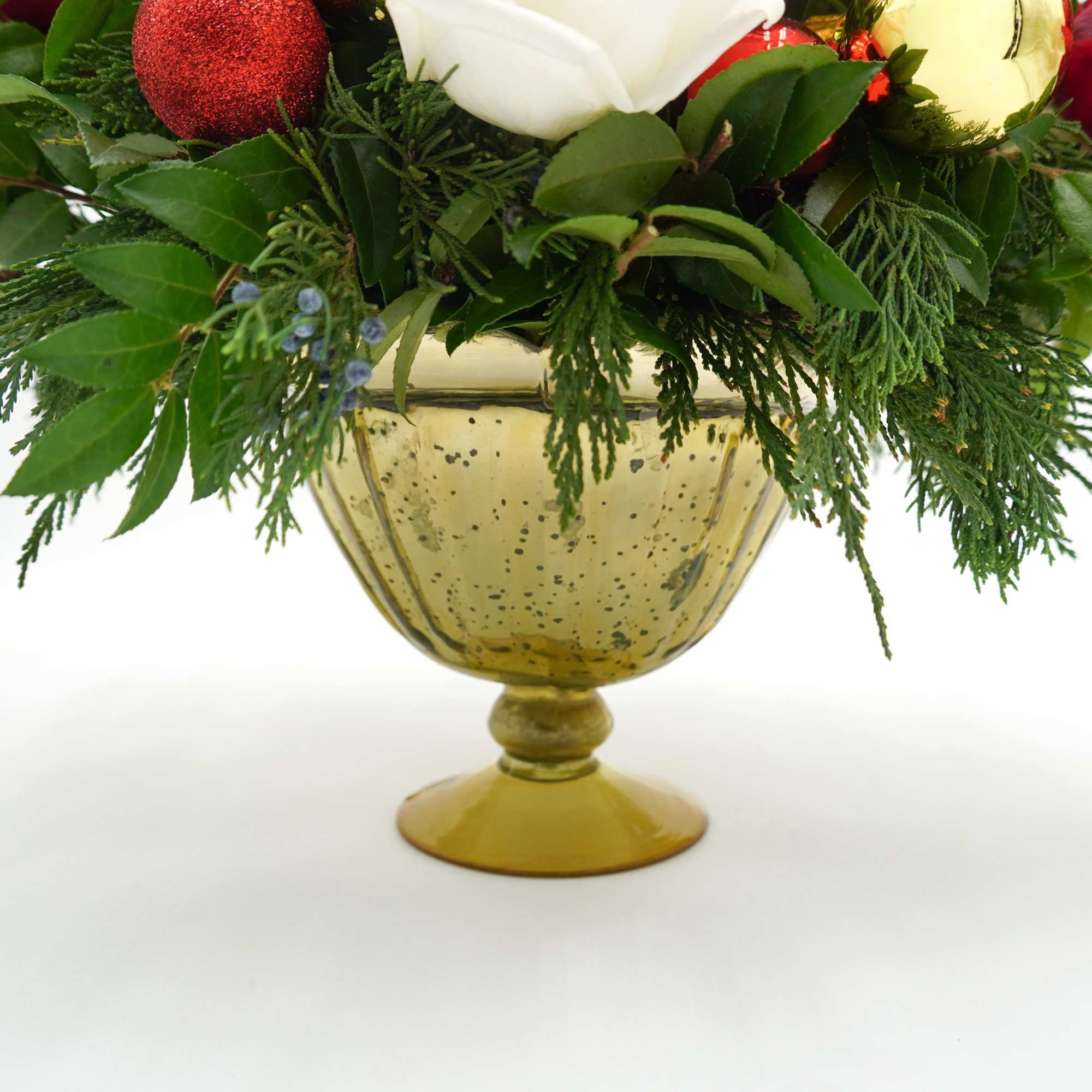 Includes white and red roses, lilies, carnations, pinecones, Christmas ornaments, and Pine