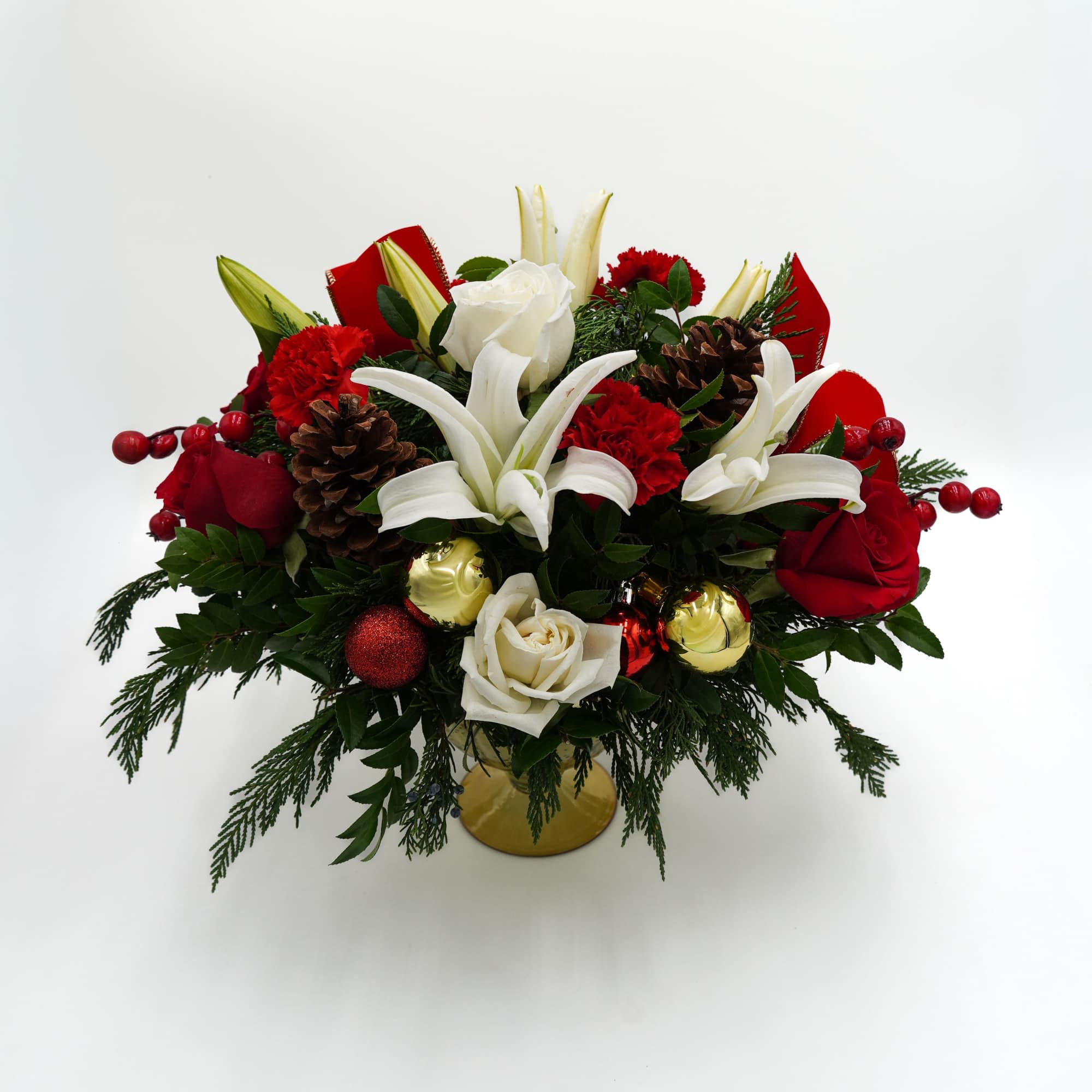 Includes white and red roses, lilies, carnations, pinecones, Christmas ornaments, and Pine