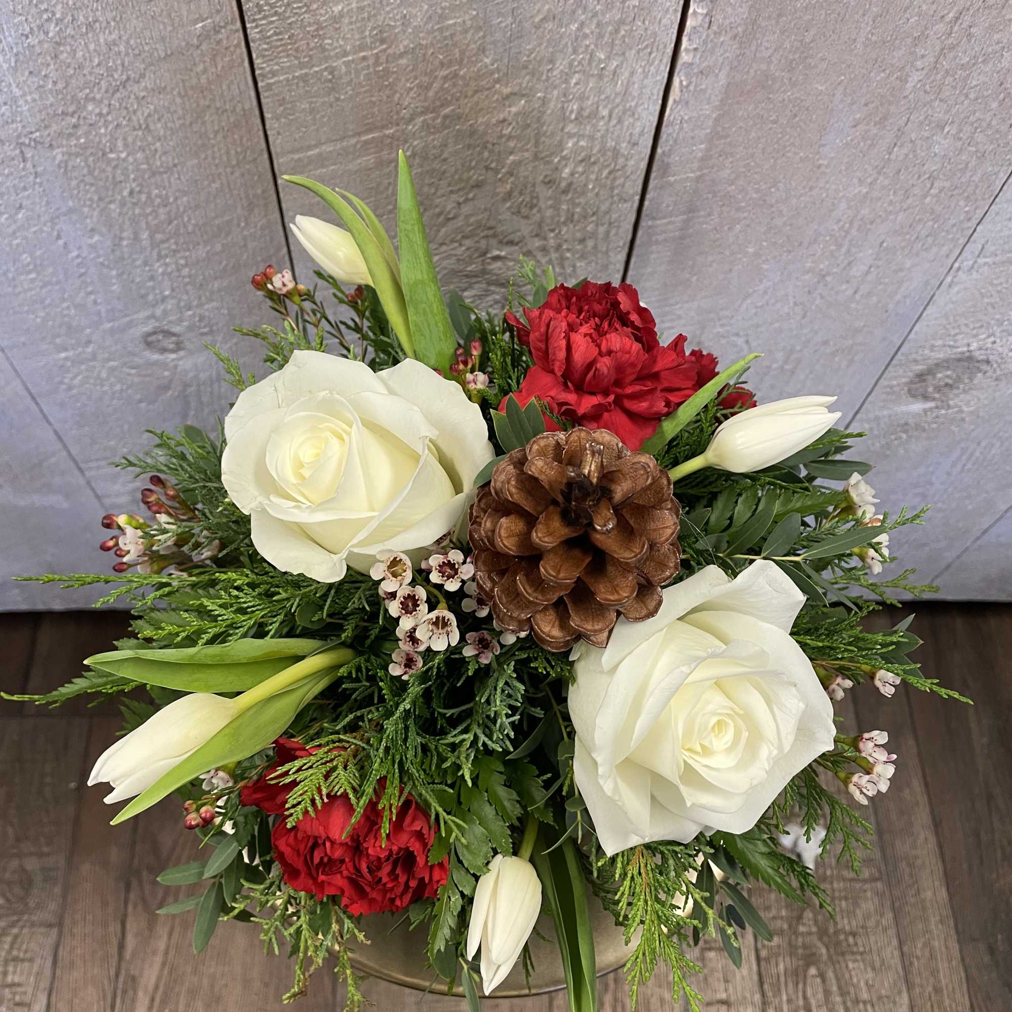 A festive arrangement in a round buffalo check container featuring a wintry