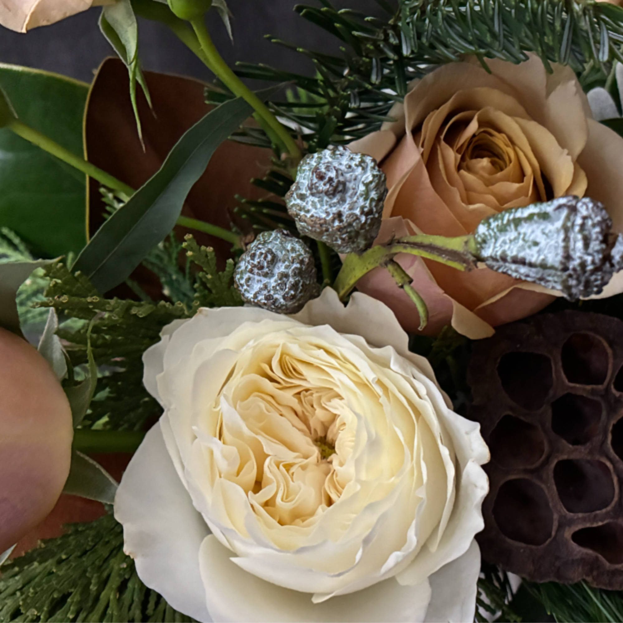 The Golden Hearth Arrangement is a luxurious mix of garden roses, wintergreens
