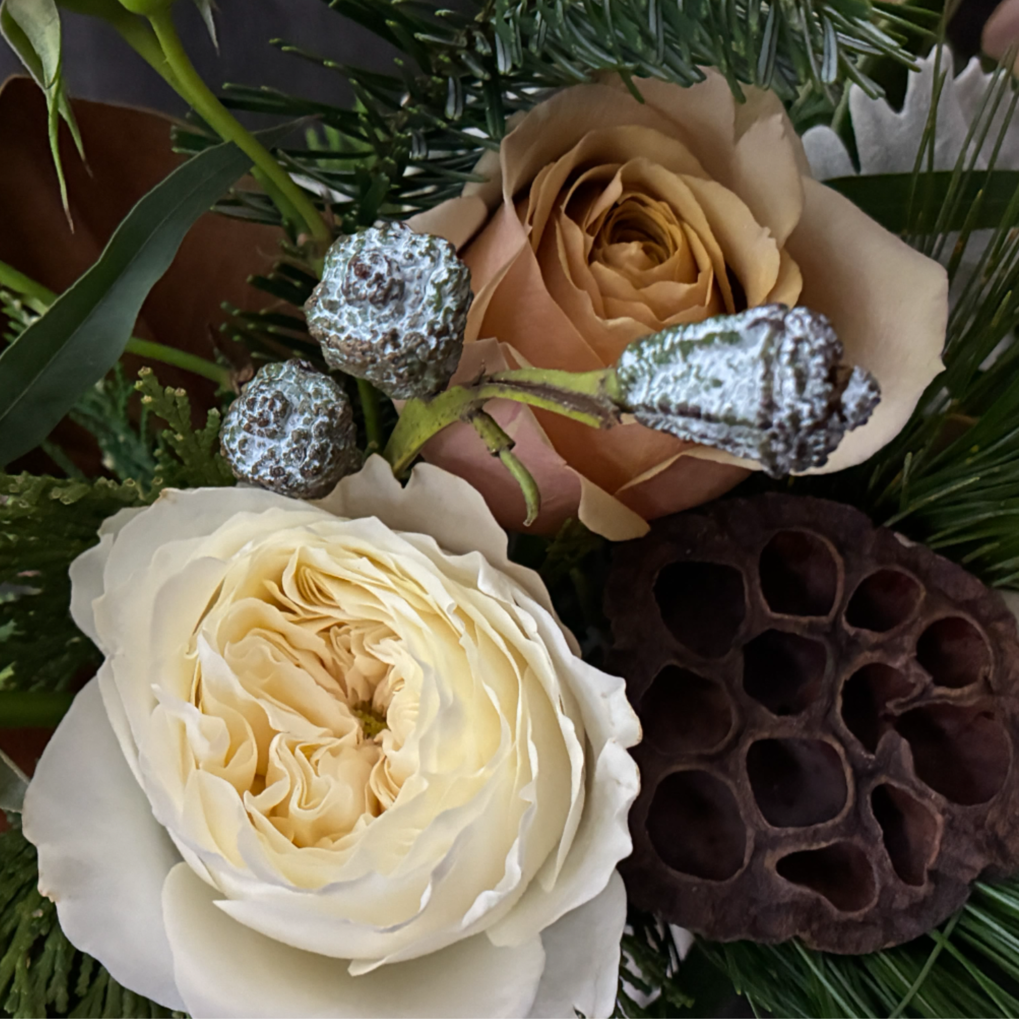 The Golden Hearth Arrangement is a luxurious mix of garden roses, wintergreens