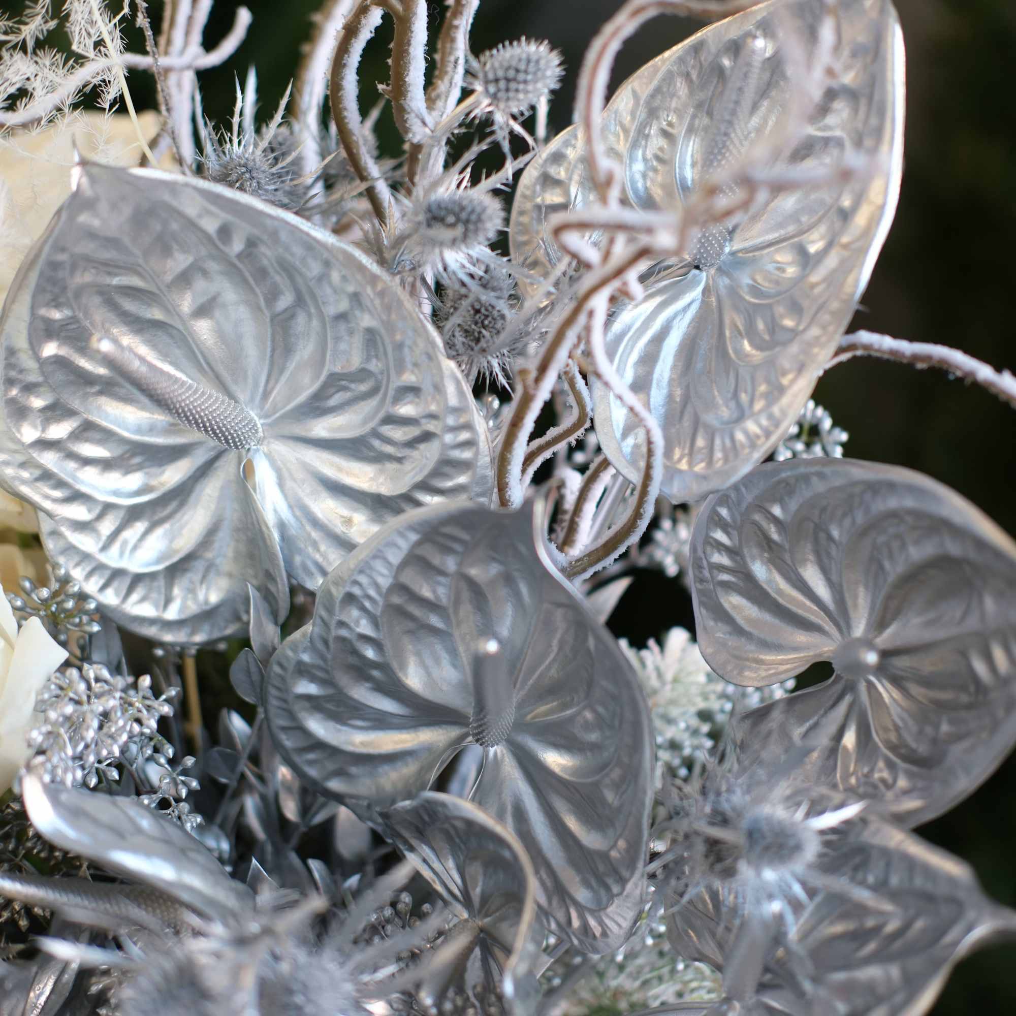 
White roses paired with sculptural silver foliage and winter branches in a
