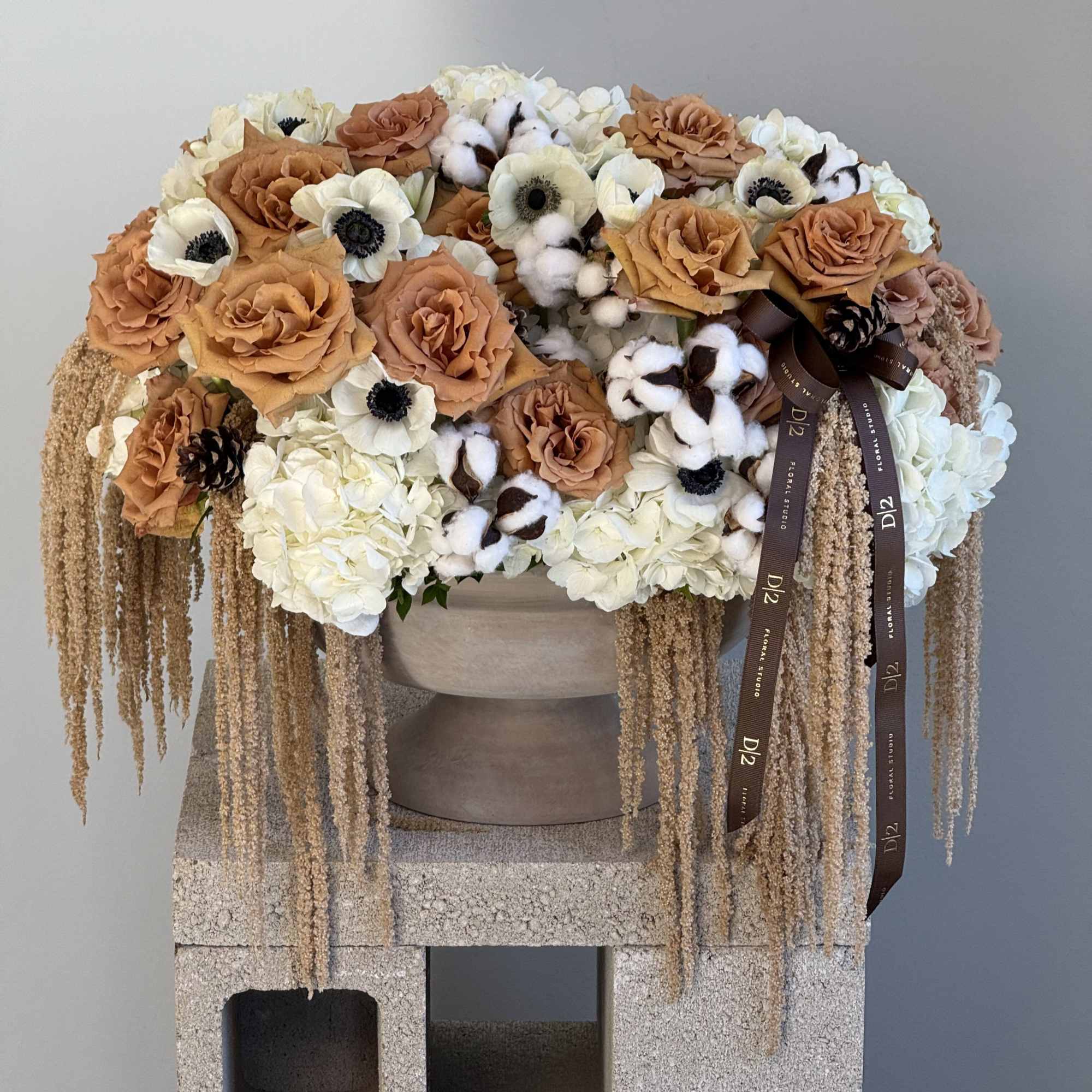 Caramel-toned roses, cotton stems, and hydrangeas with cascading amaranthus for a warm