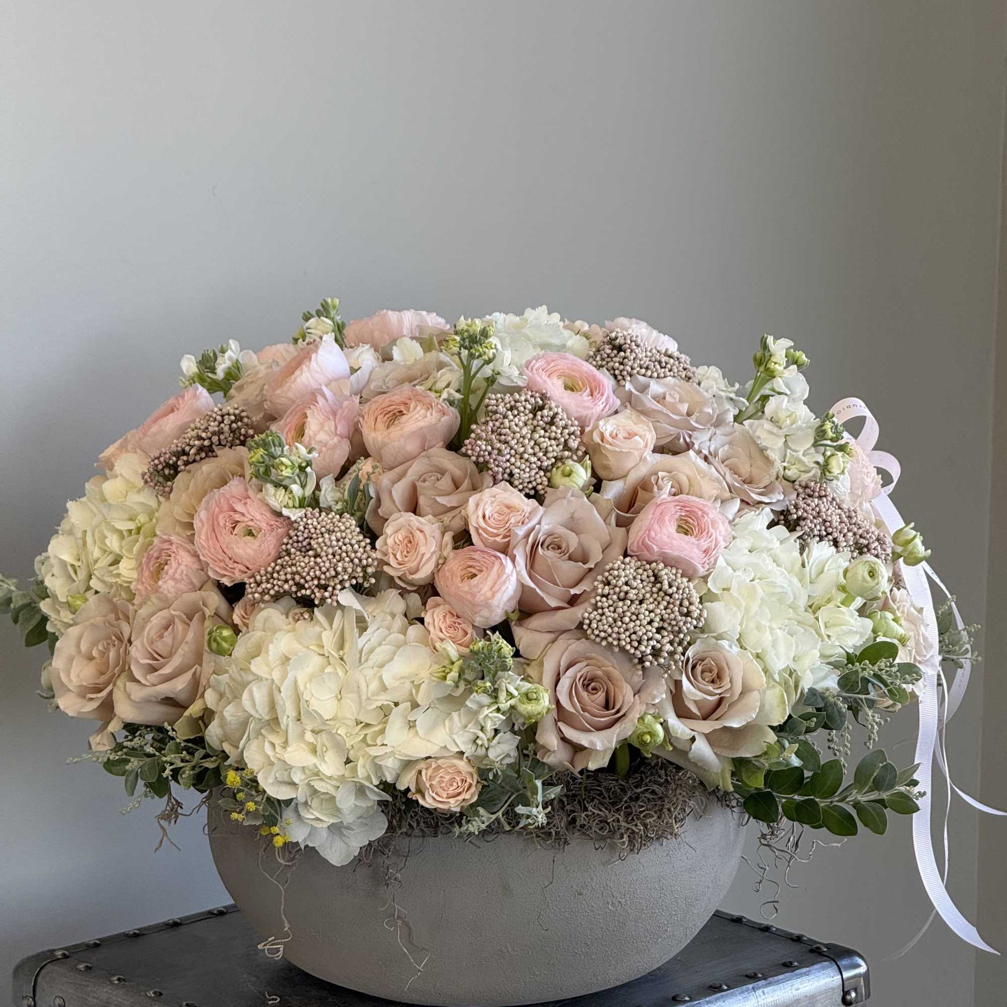 A soft mix of blush roses, ranunculus, hydrangeas, and textured florals in