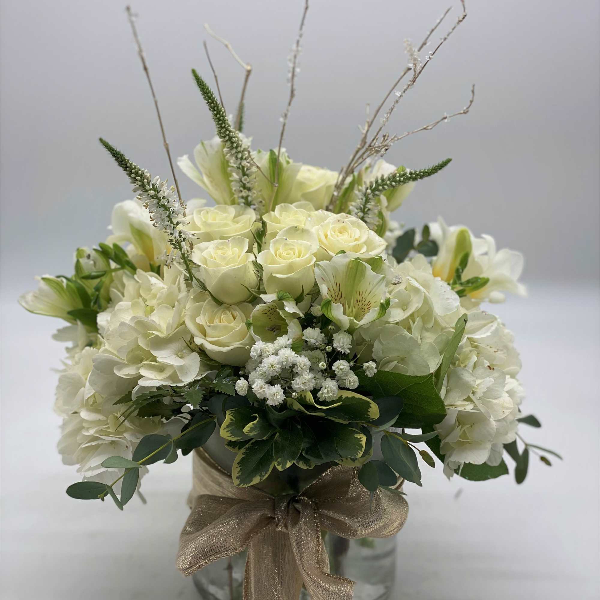A lush mix of fresh white flowers arranged in a cylinder vase