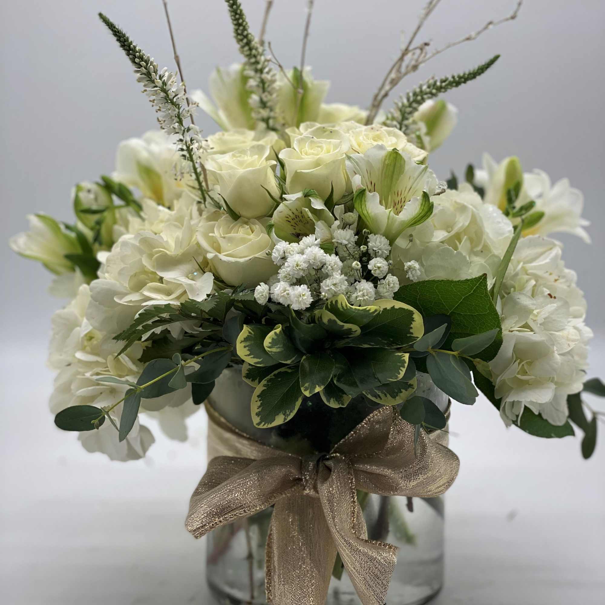 A lush mix of fresh white flowers arranged in a cylinder vase