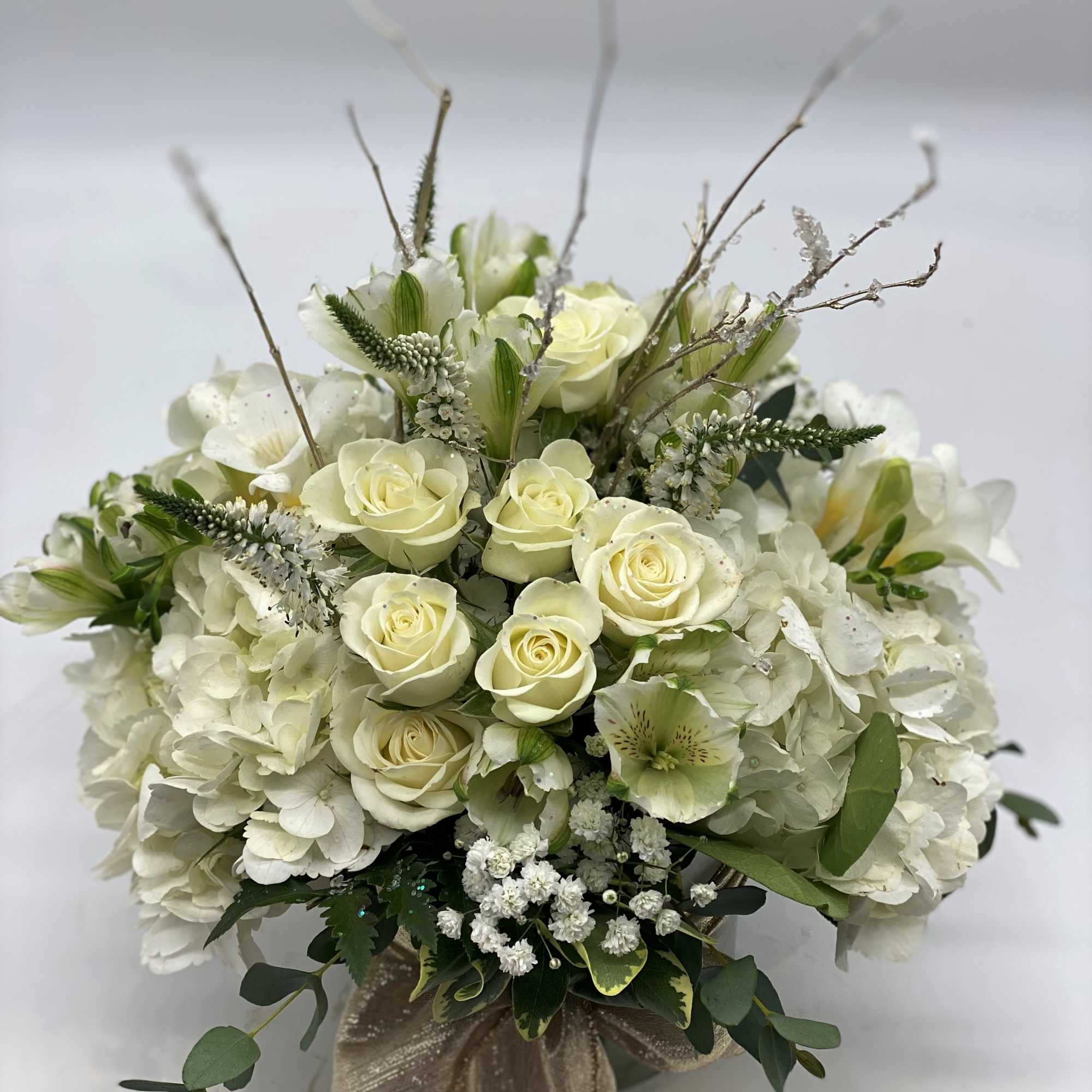 A lush mix of fresh white flowers arranged in a cylinder vase
