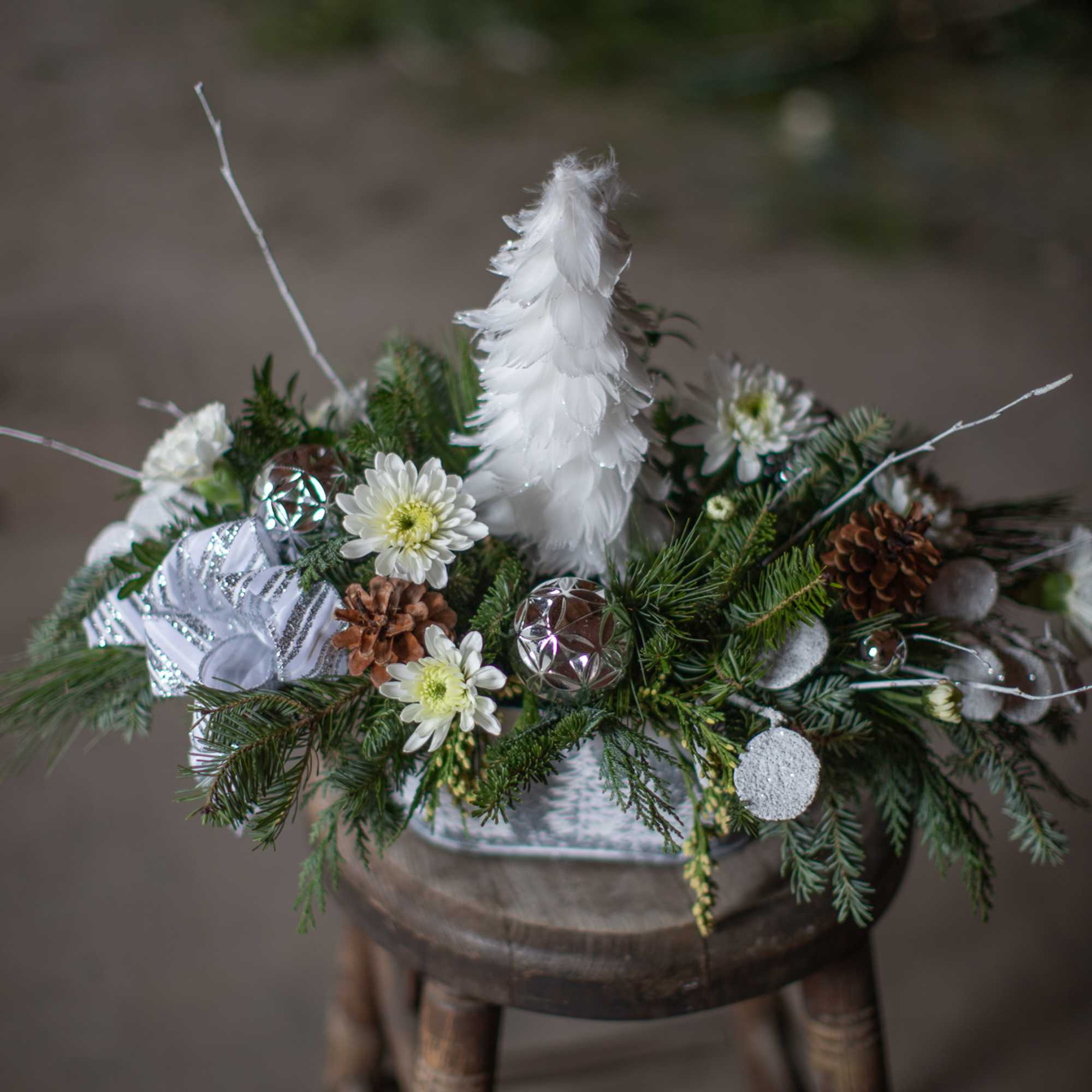 A beautiful assortment of winter&#039;s finest greenery are artfully arranged in a