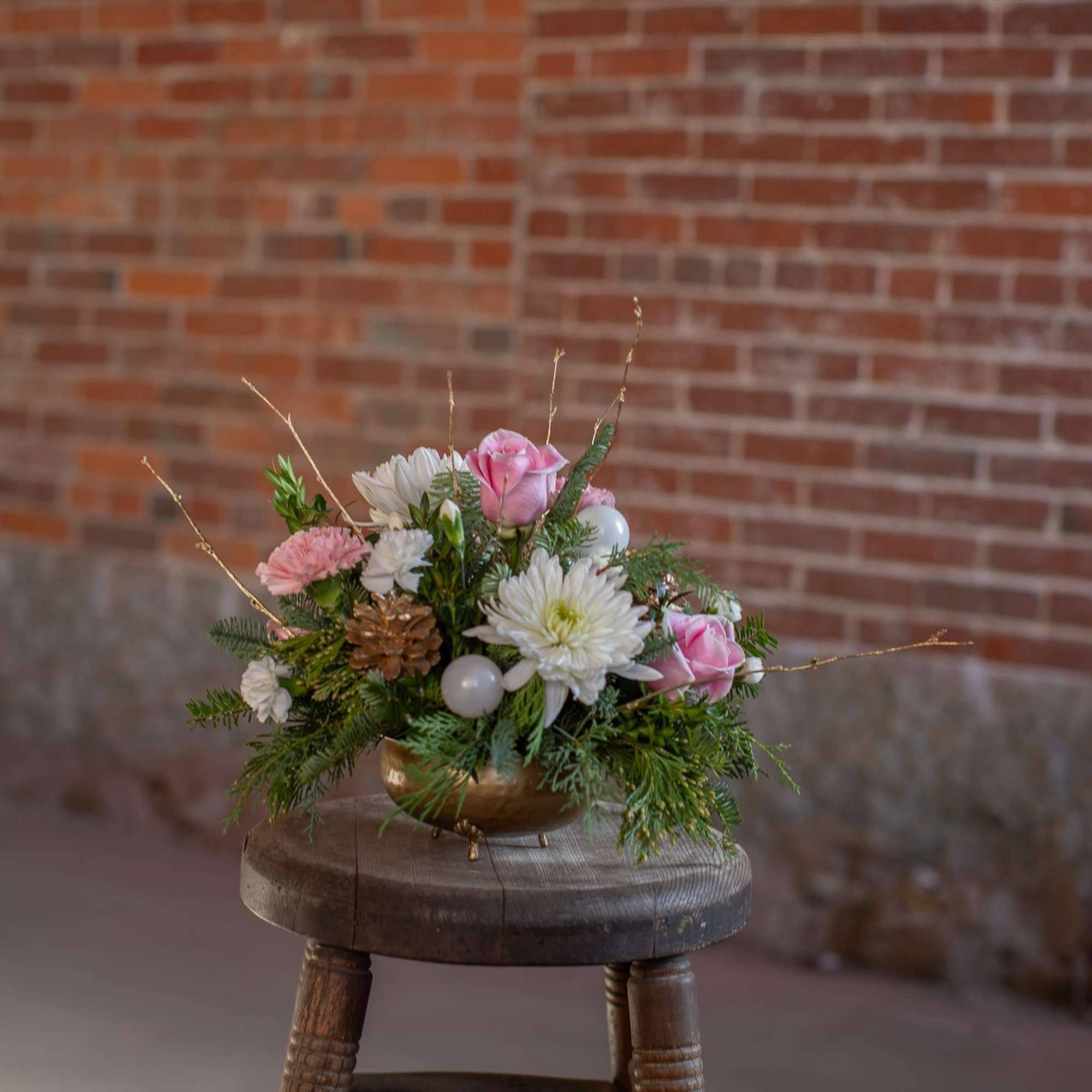 Artfully arranged winter foliage varieties are nested in a lovely golden bowl.