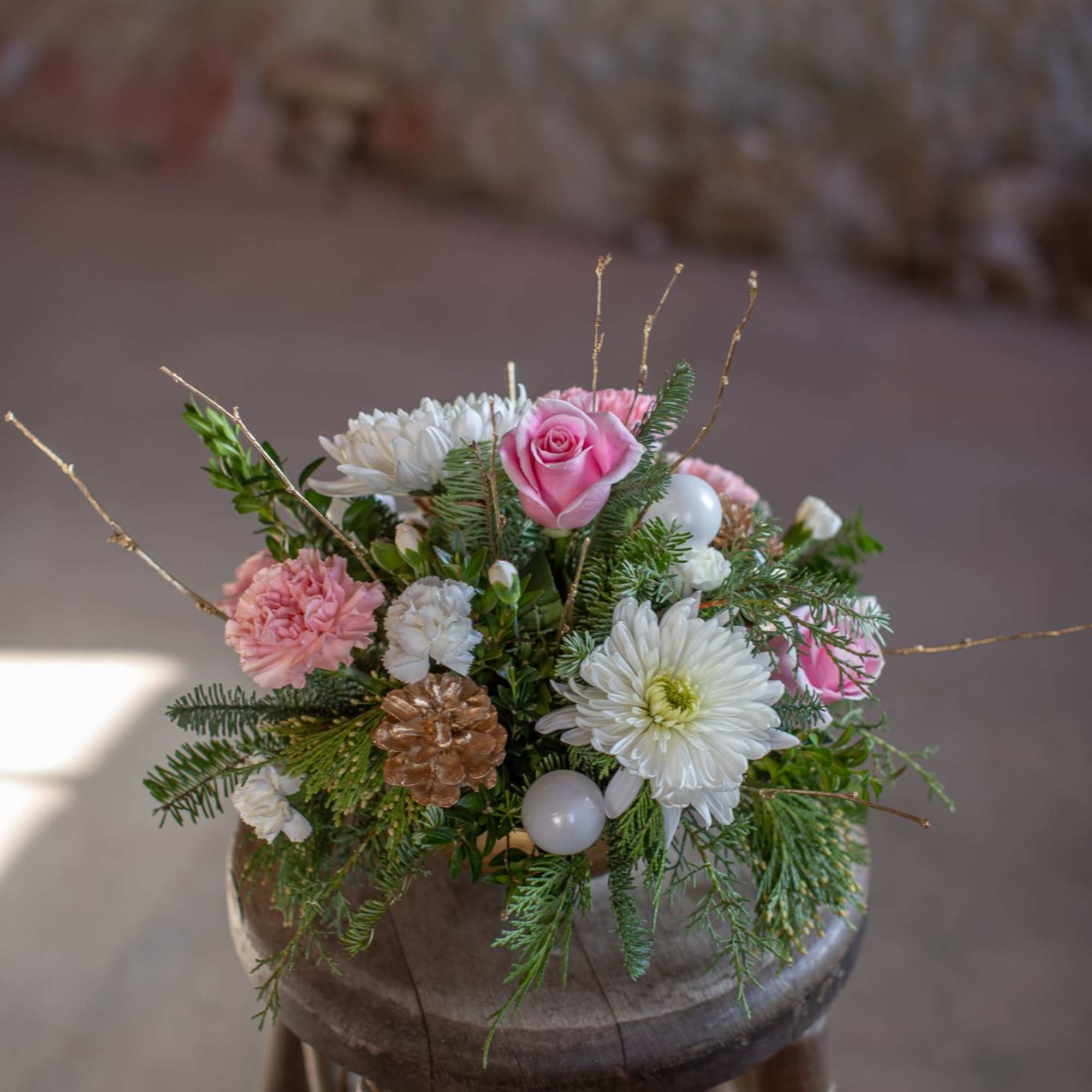 Artfully arranged winter foliage varieties are nested in a lovely golden bowl.