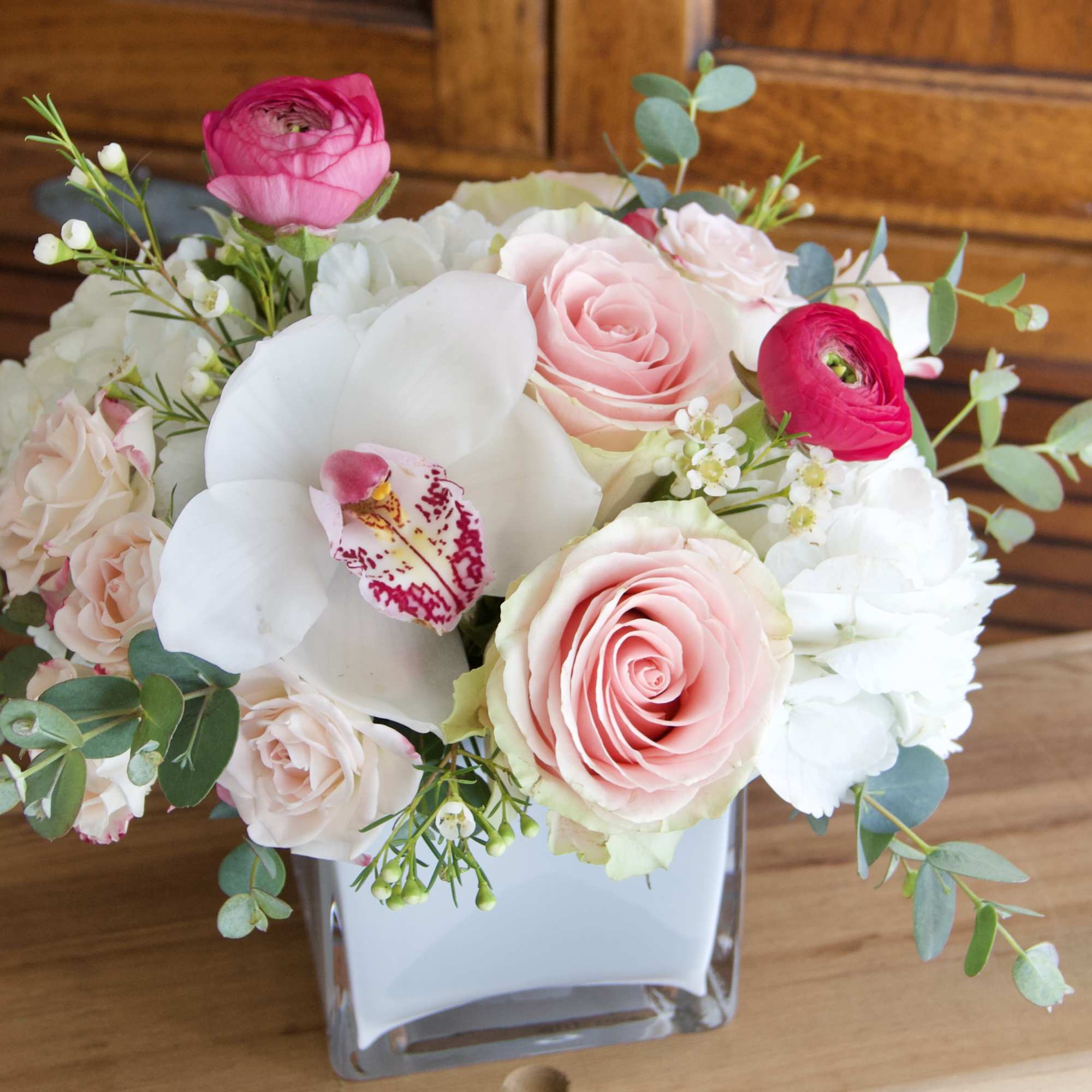 A compact, more modern style arrangement featuring roses, spray roses, hydrangea, and