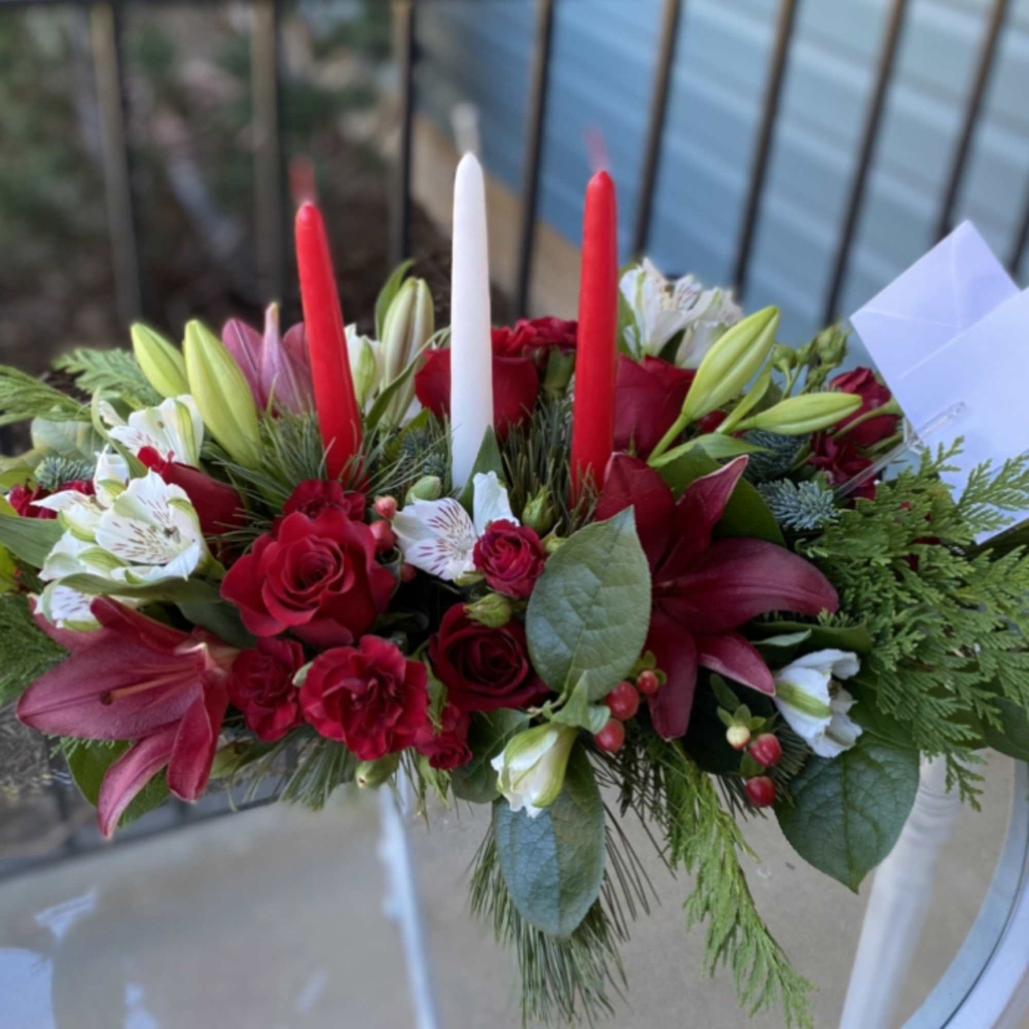 Red, and white flowers in lush Christmas greens make up this lovely