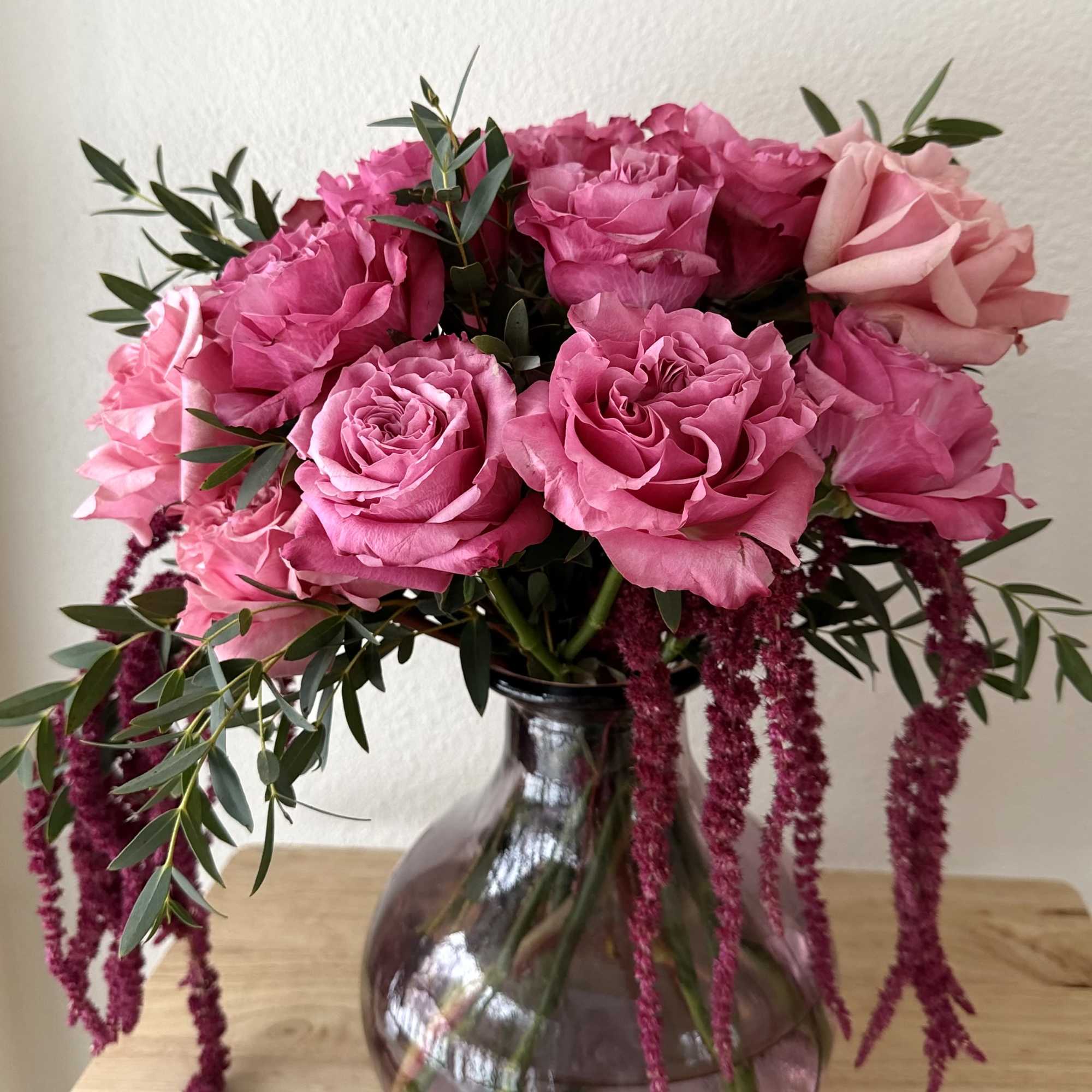 A lush, vibrant arrangement of rich pink roses paired with cascading amaranthus