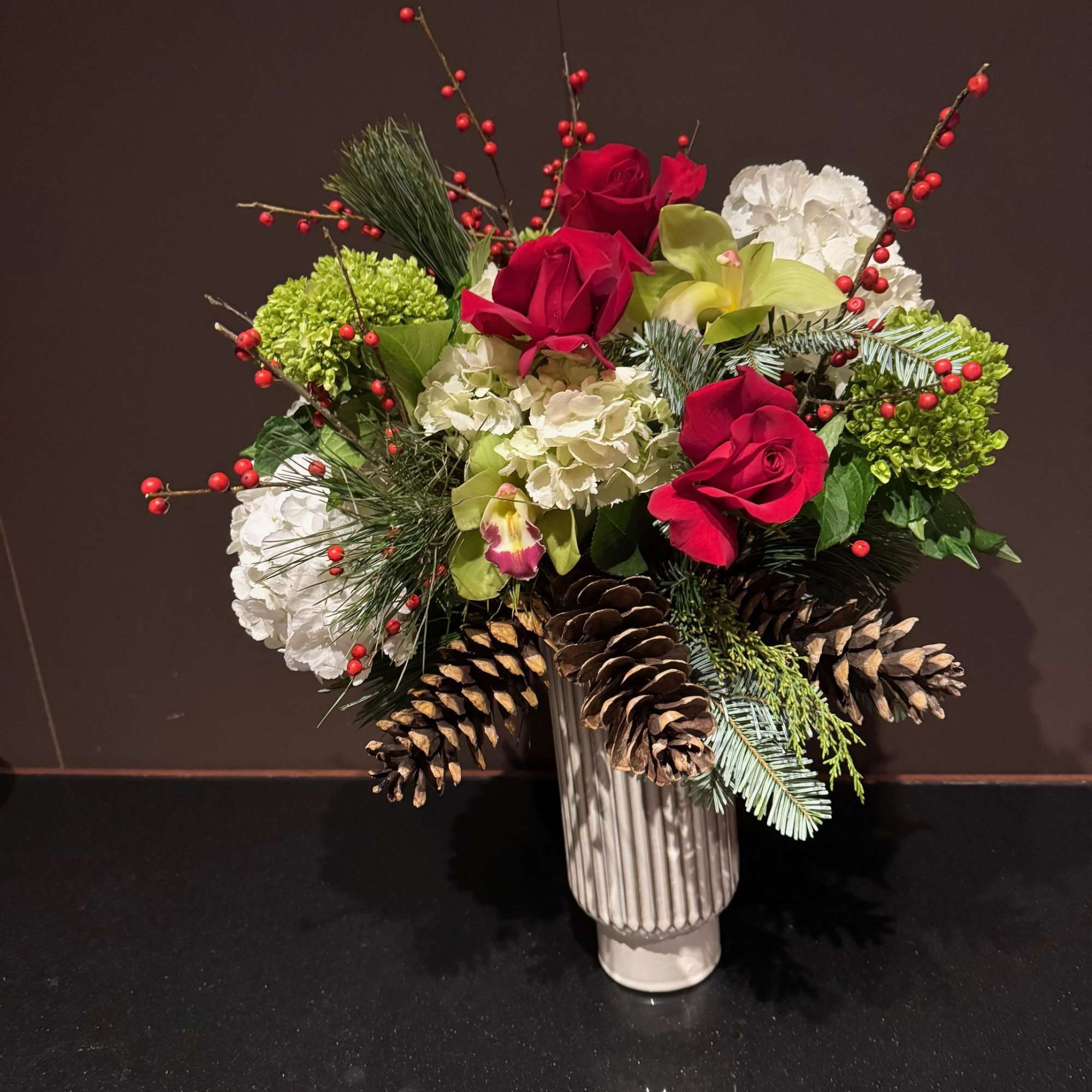 A full and festive arrangement of red, green, and white blooms. 