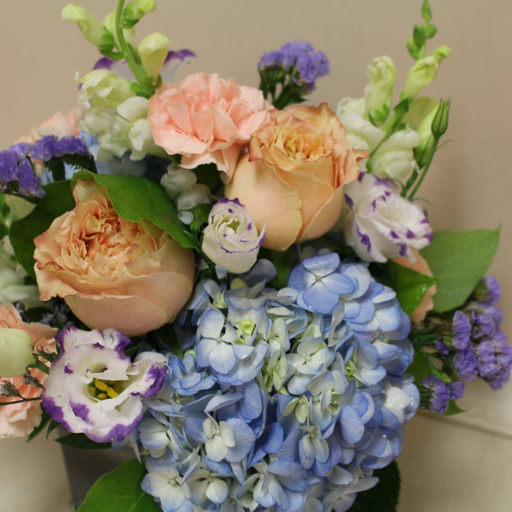 a delicate arrangement, soft peaches and blues in a twig based basket.