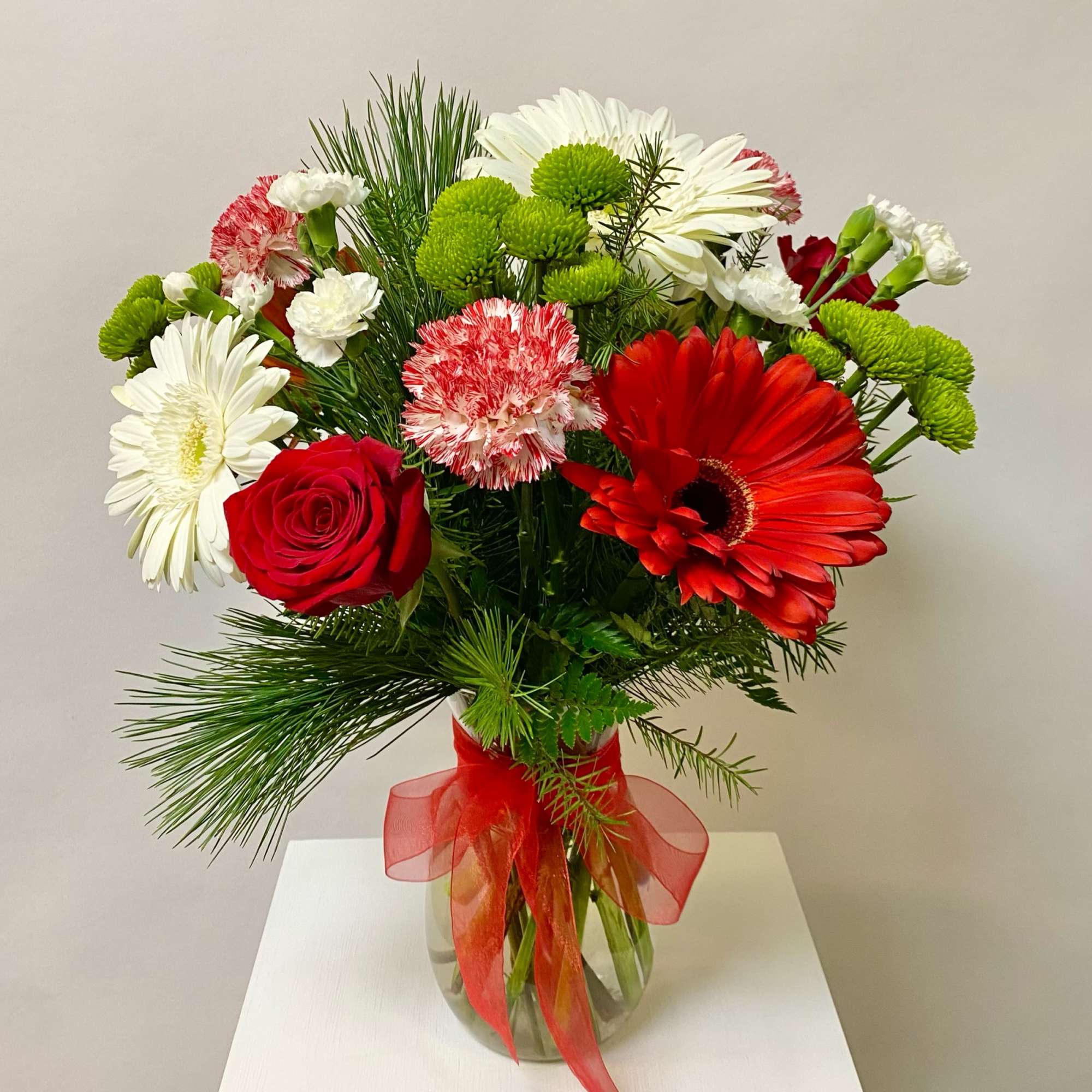 This Medium Tall Arrangement Incudes Christmas Greens, Red Gerbera Daisies, White Gerbera