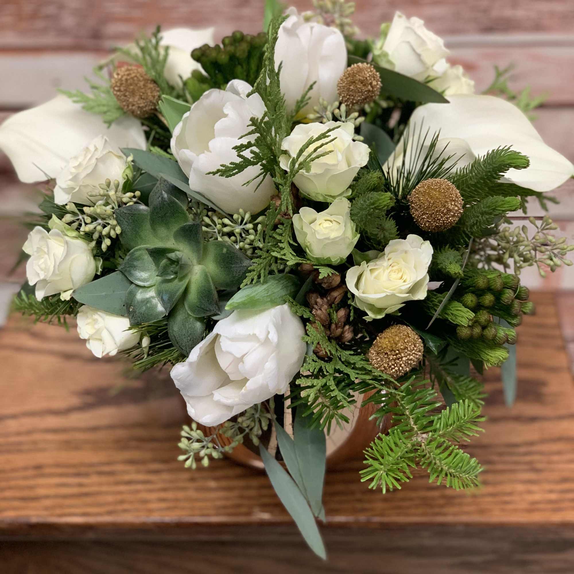 A delicate white arrangement in a golden vase with gold gold and