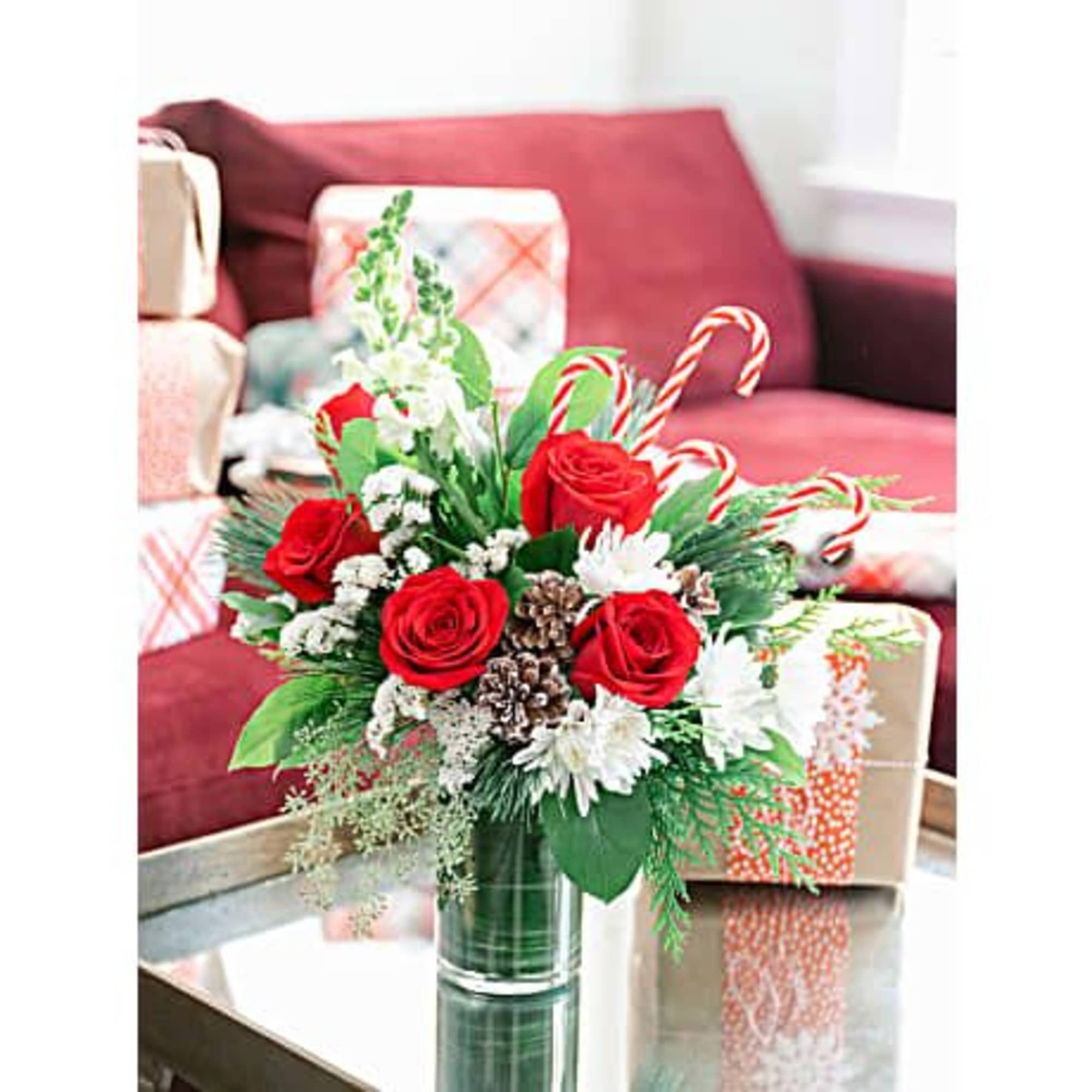 Red roses, creme roses and white snapdragons are wrapped in a variegated