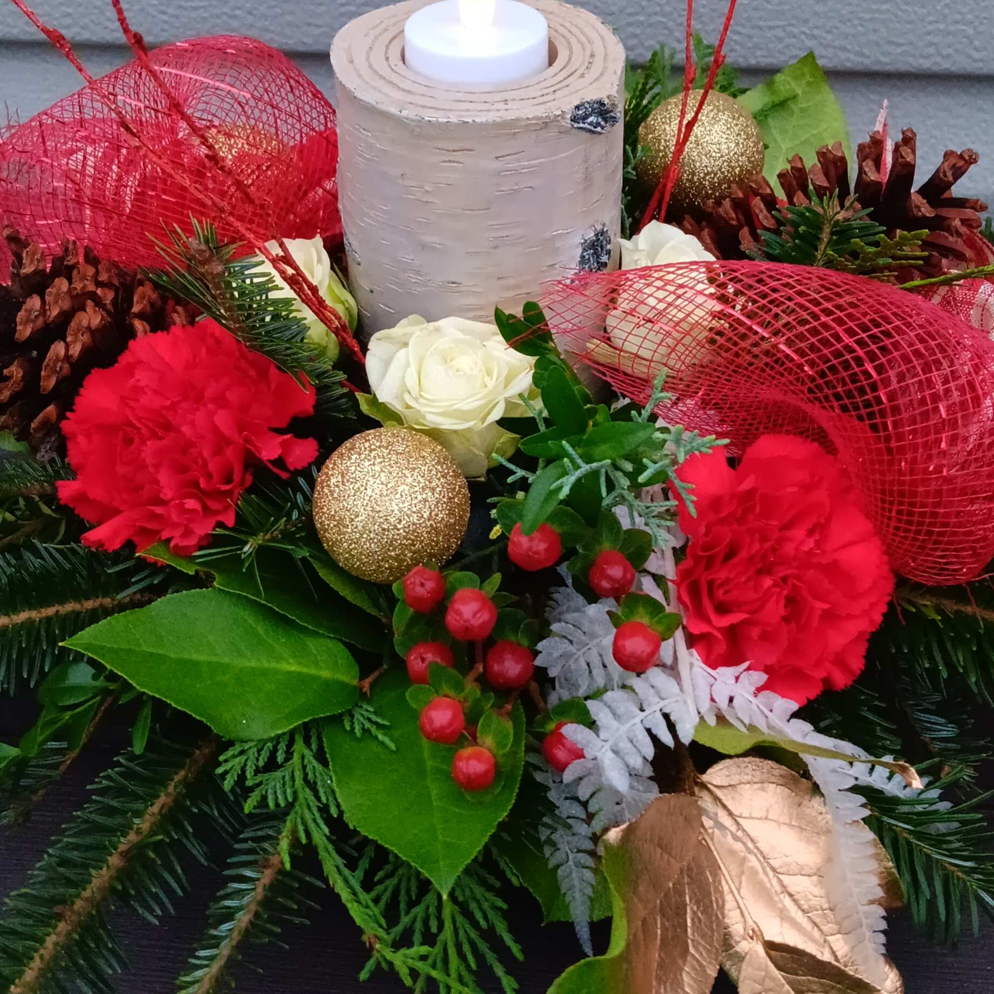 Round holiday  centerpiece with faux birch candle holder, red carnations, spray