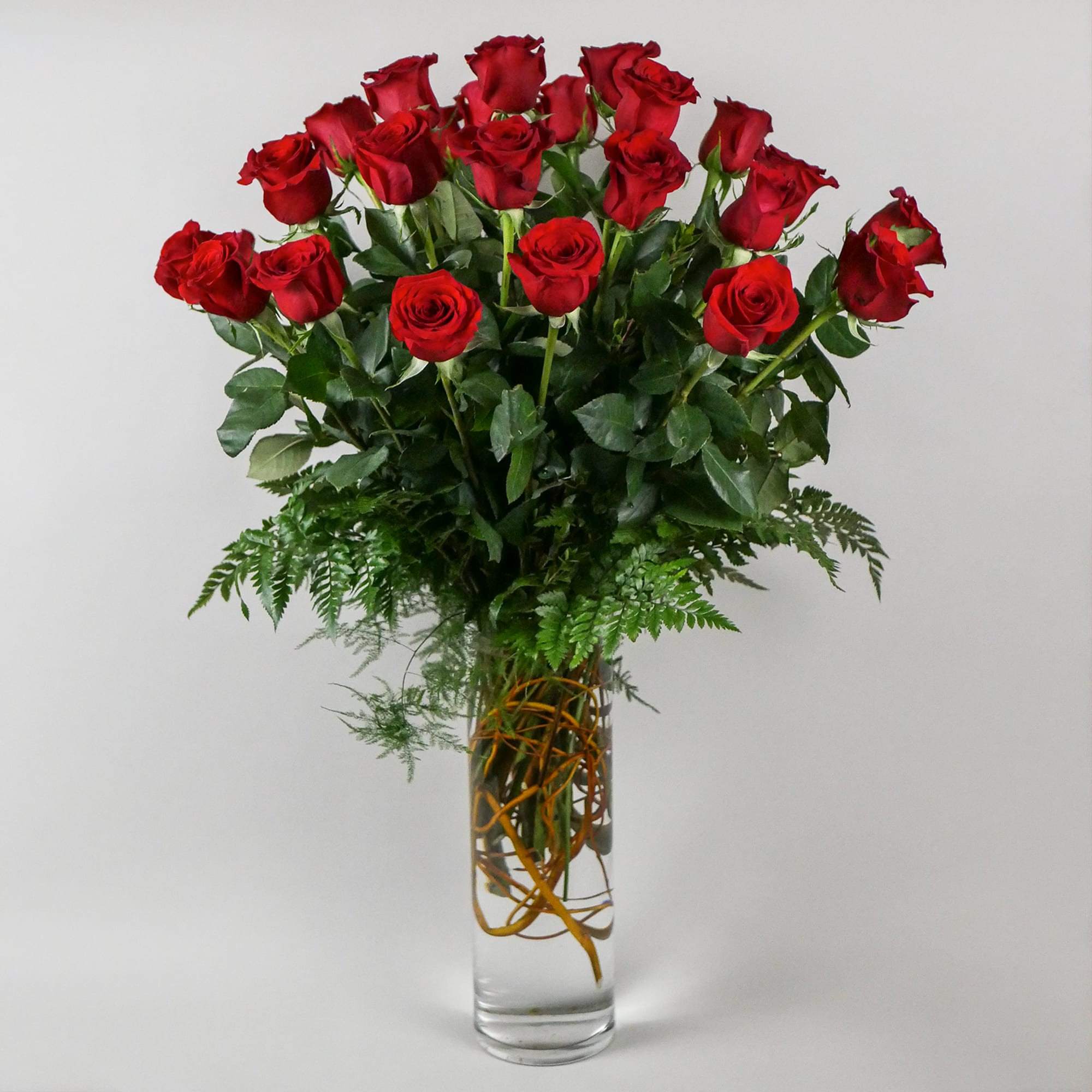 This romantic arrangement features our premium red roses with lush greens in
