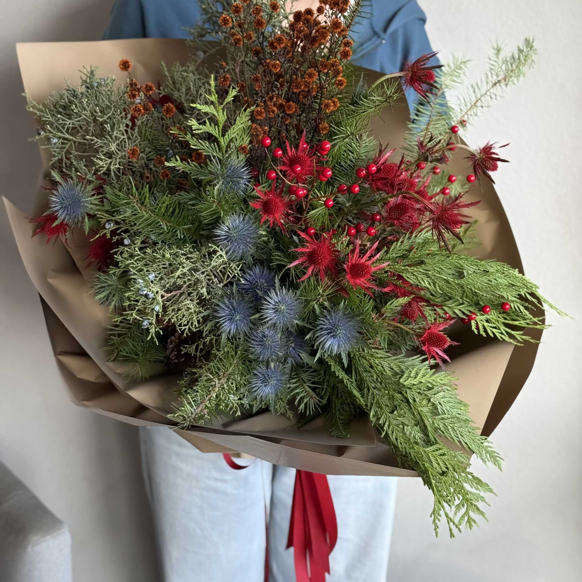 A festive and modern handheld holiday bouquet featuring striking blue and red