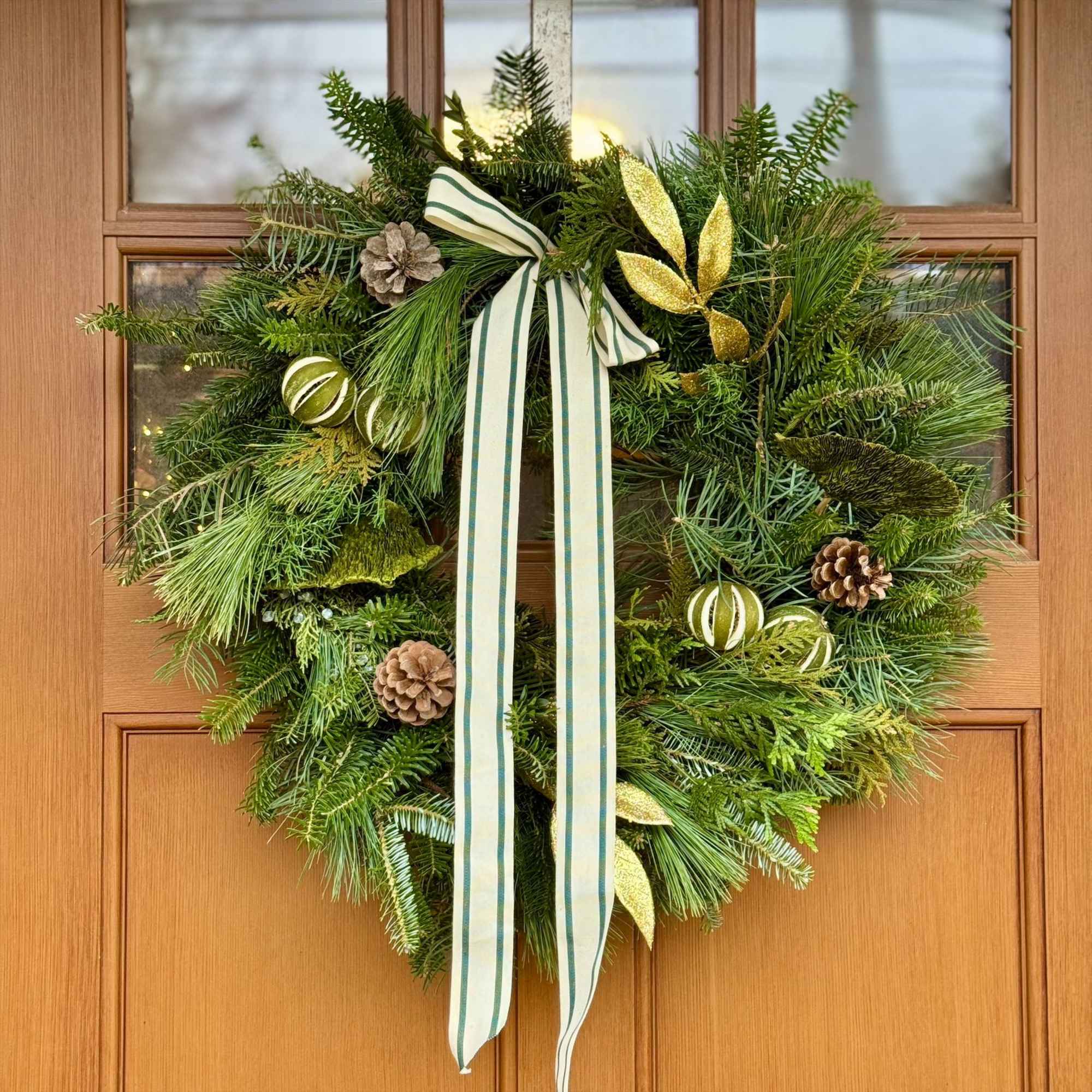 This fresh evergreen wreath is locally handmade and then accented with ribbon