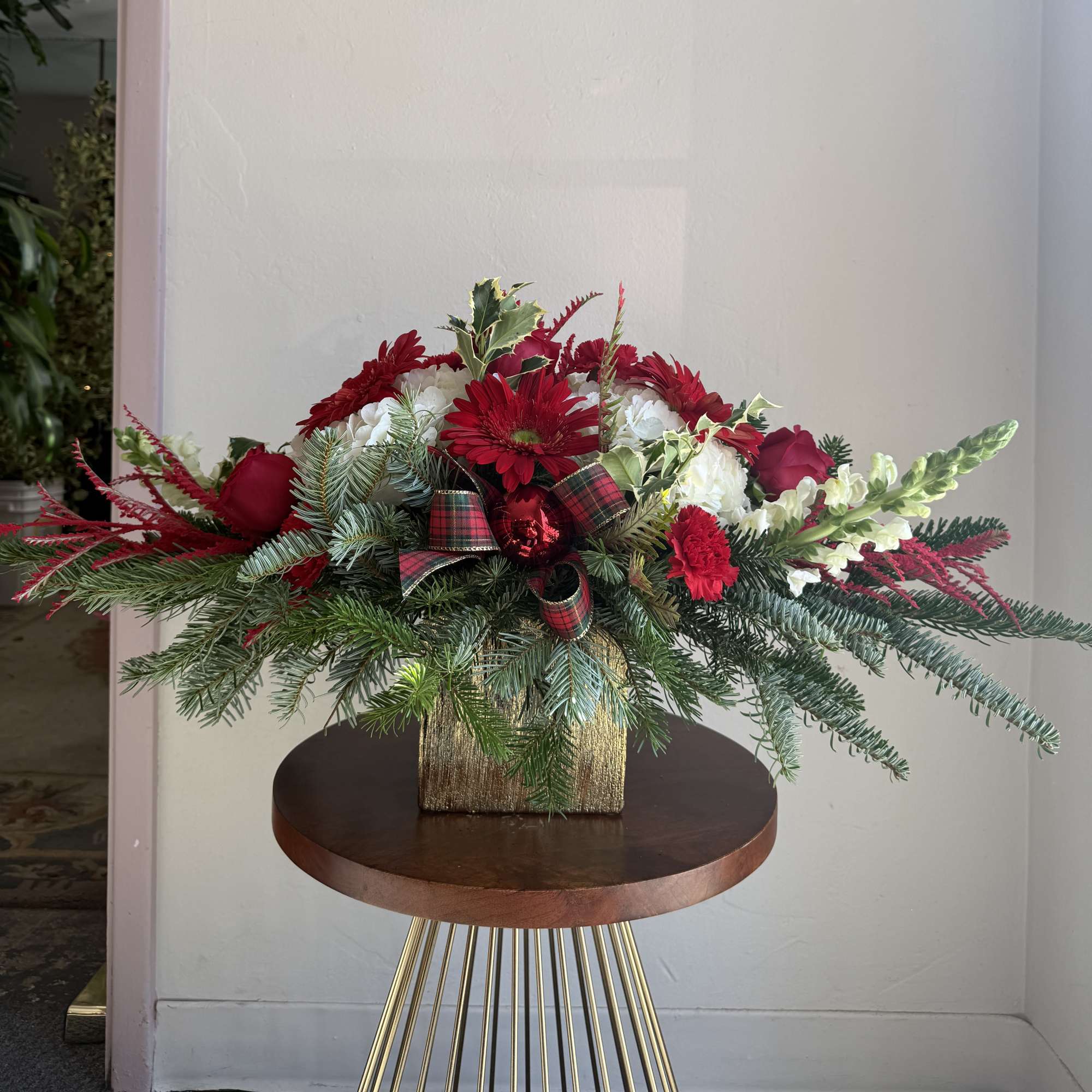 Christmas centerpiece in a specialty gold cube vase filled with hydranges, roses